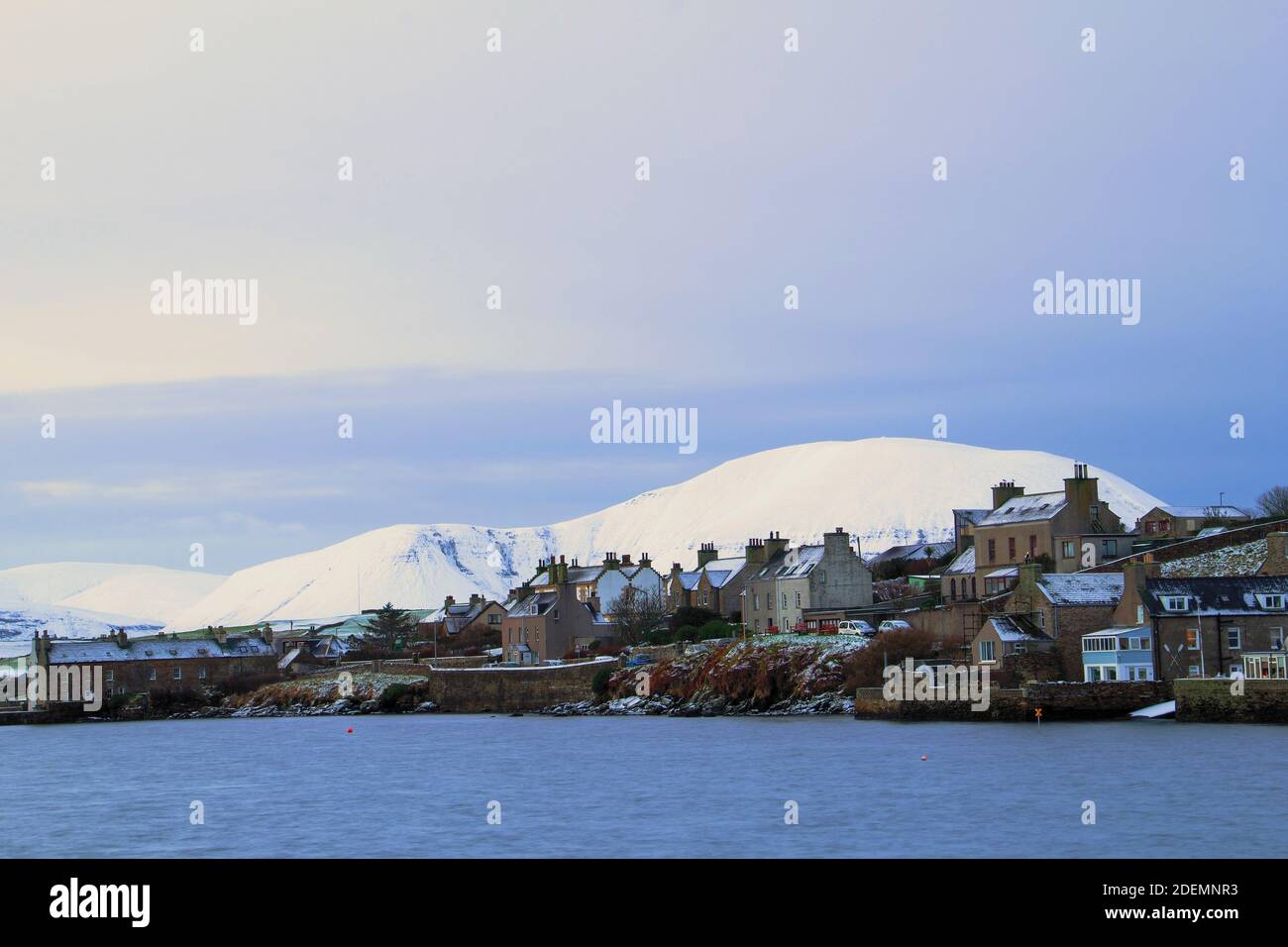 Small scottish town in winter scene with houses and big hill covered with snow Stock Photo
