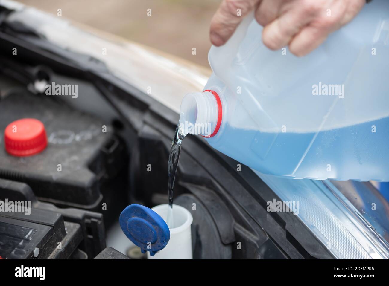 Hands of mechanic pouring blue windshield washer fluid in a car Stock