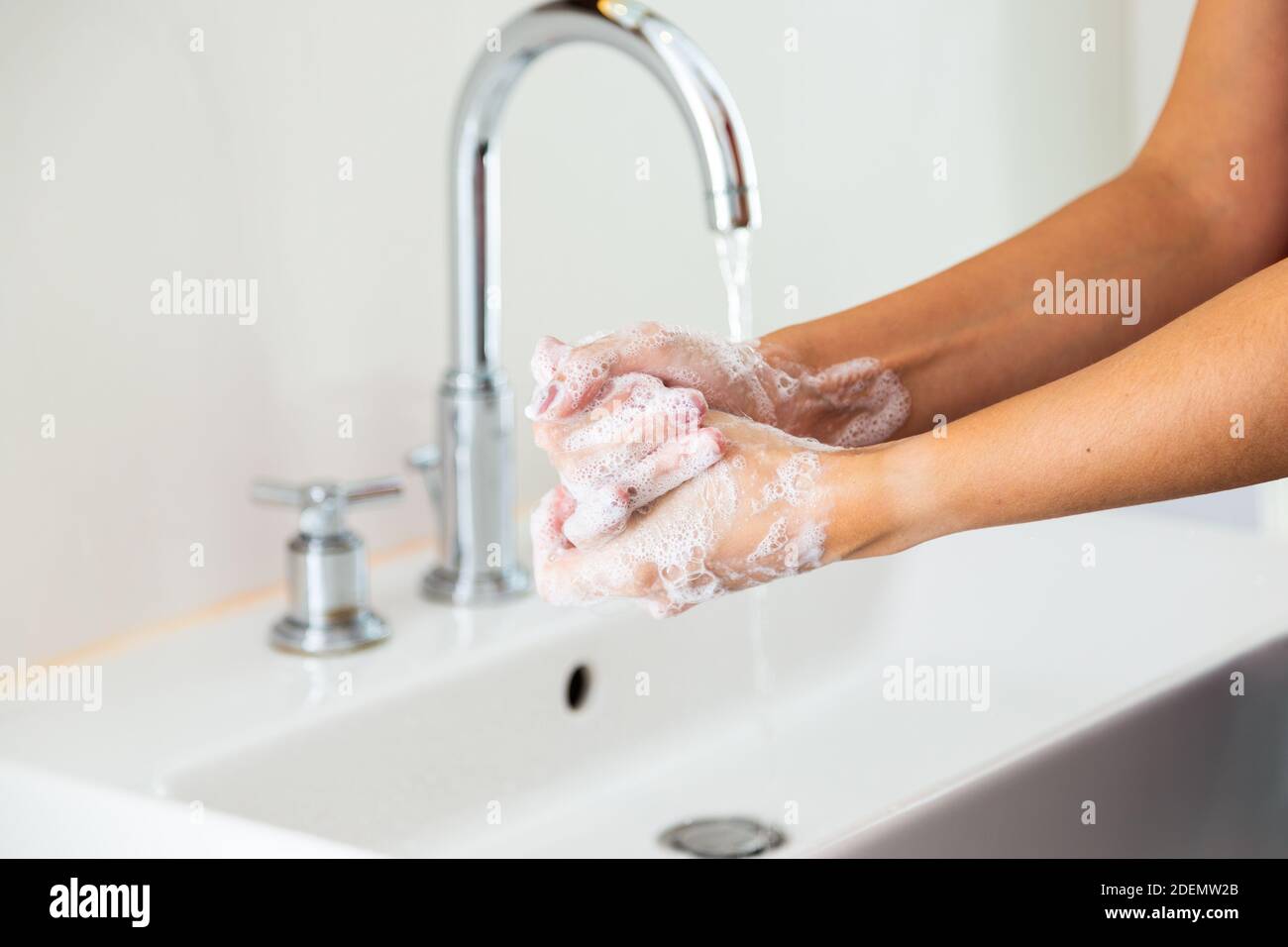 Woman washing her hands with soap in bathroom from side Stock Photo - Alamy