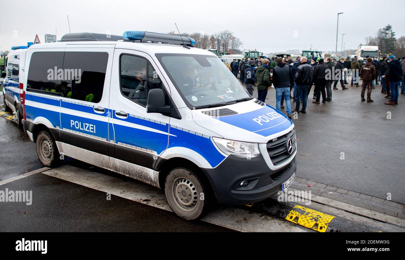 Cloppenburg, Germany. 01st Dec, 2020. Police vehicles are parked at the  access road to the central warehouse of Lidl, which is blocked by farmers  with their tractors. Hundreds of farmers have continued