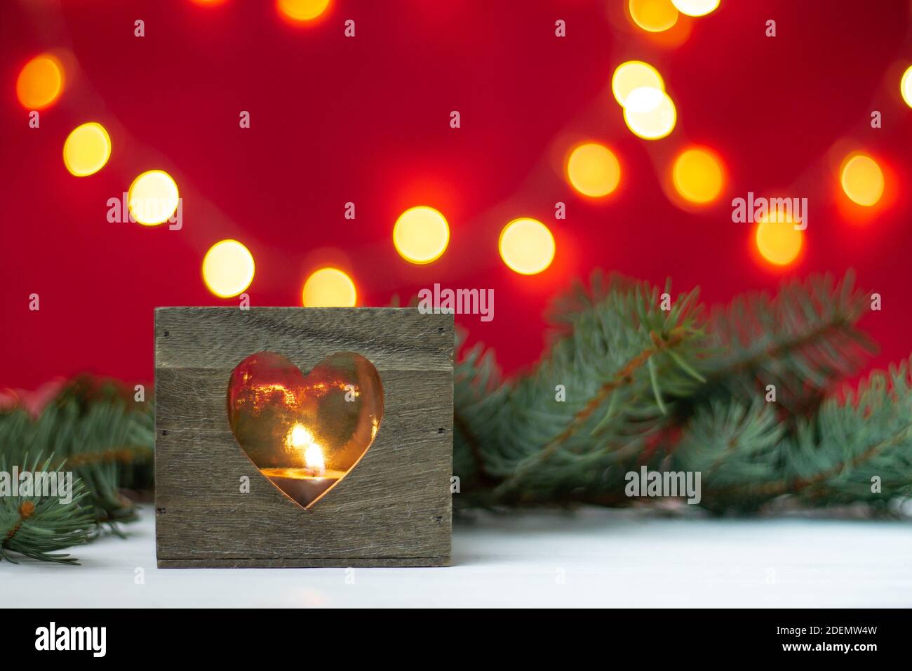Wooden candlestick with Christmas tree branches and bokeh on a red background. Merry christmas and a happy new year Stock Photo