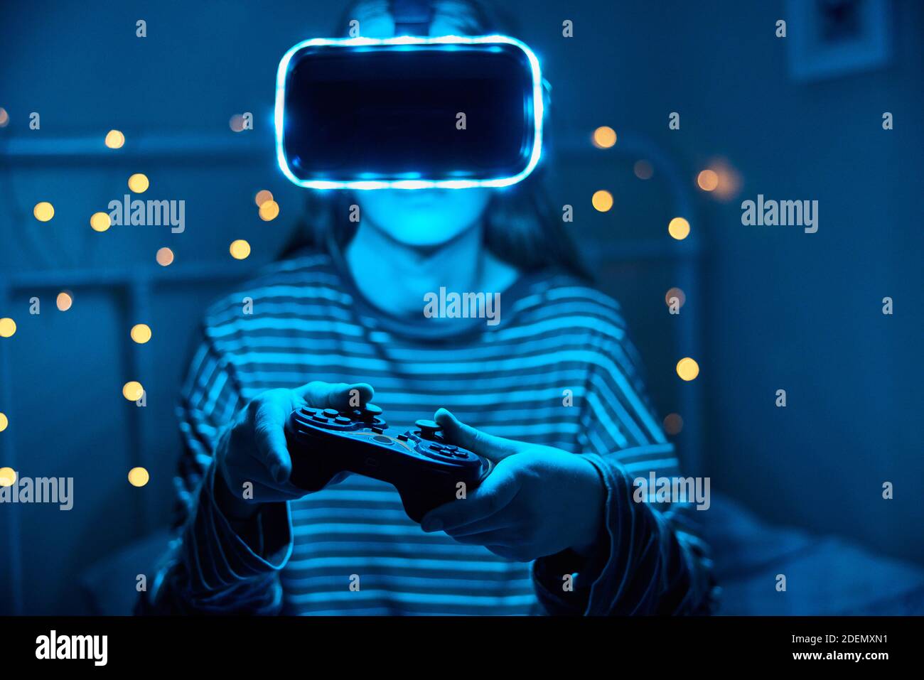 Teenage Girl Playing Video Game At Home In Bedroom Wearing Virtual Reality Headset At Night Stock Photo