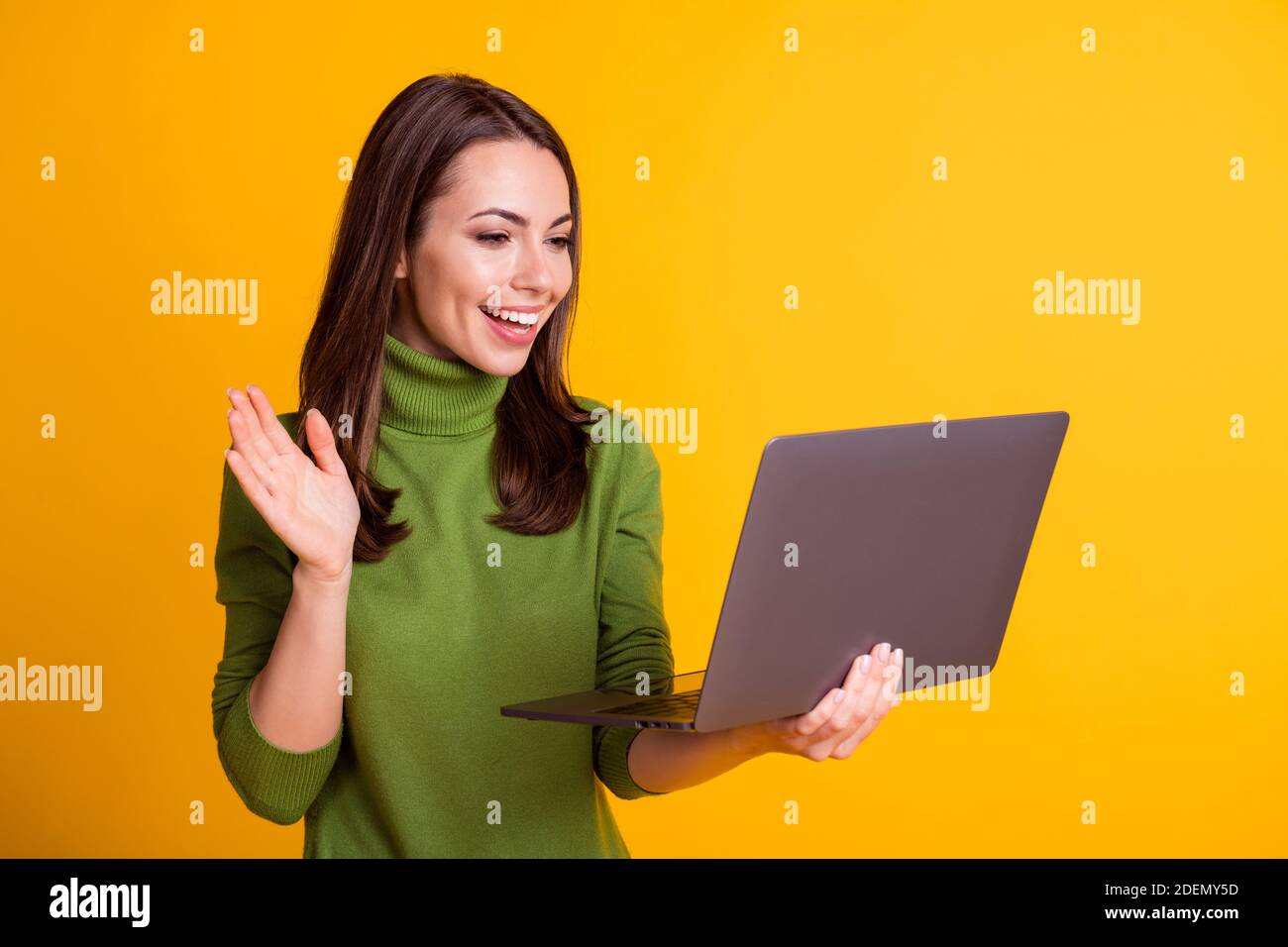 Photo of attractive lady self isolation hold notebook waving arm video call  wear green sweater isolated yellow color background Stock Photo - Alamy