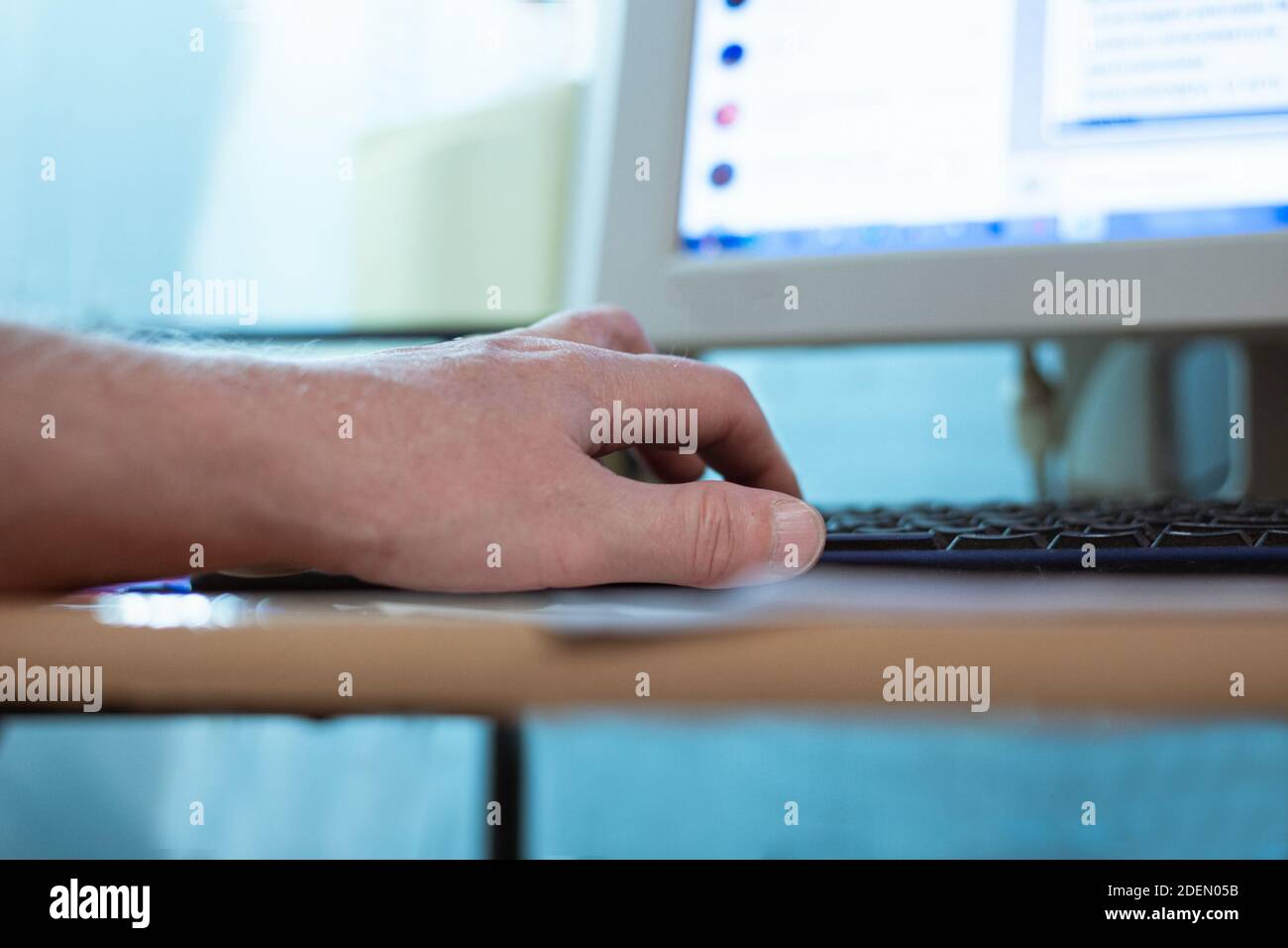 man typing on computer keyboard with his left hand, remote work at home, blurred background Stock Photo