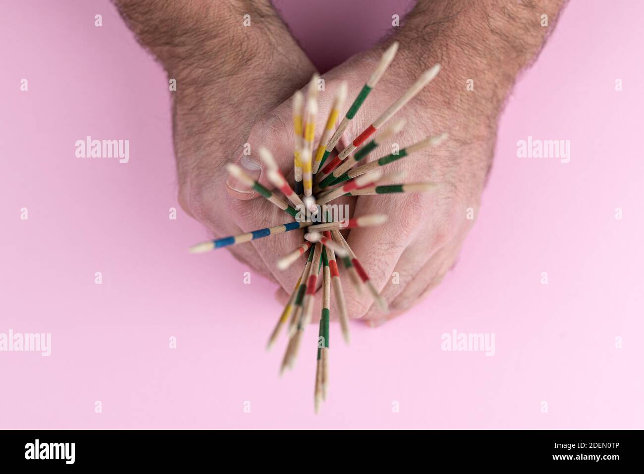 top view of hands holding mikado pick-up sticks against pink background Stock Photo