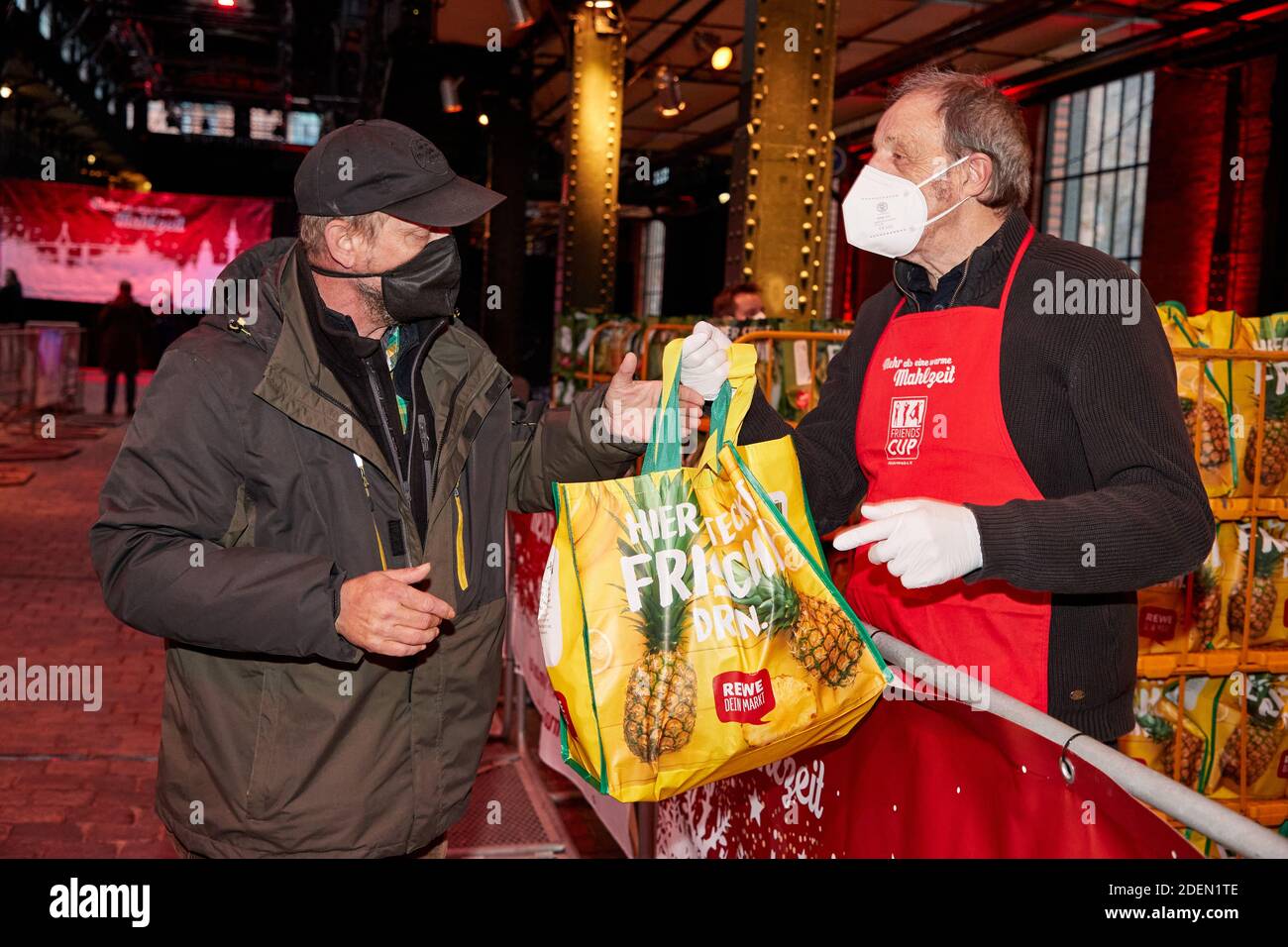 Hamburg, Germany. 01st Dec, 2020. Fred Jaschner (l), homeless person, receives a bag from Rolf Fuhrmann, journalist, in the fish auction hall as part of the aid campaign of the Friends Cup supporters' association. For the relief action a 'Bag of Happiness' for 400 needy and homeless people were driven in busses from the Messberg to the fish auction hall to receive their gift bag with things of daily use. Credit: Georg Wendt/dpa/Alamy Live News Stock Photo