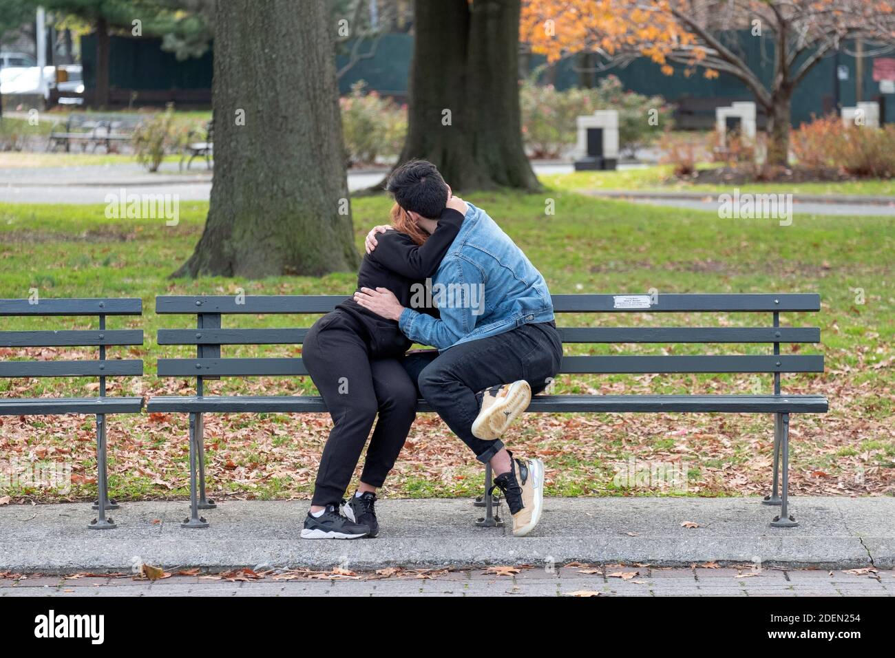 An unidentifiable couple embrace and kiss on a mild autumn day. In Flushing Meadows Corona Park in Queens, New York. Stock Photo