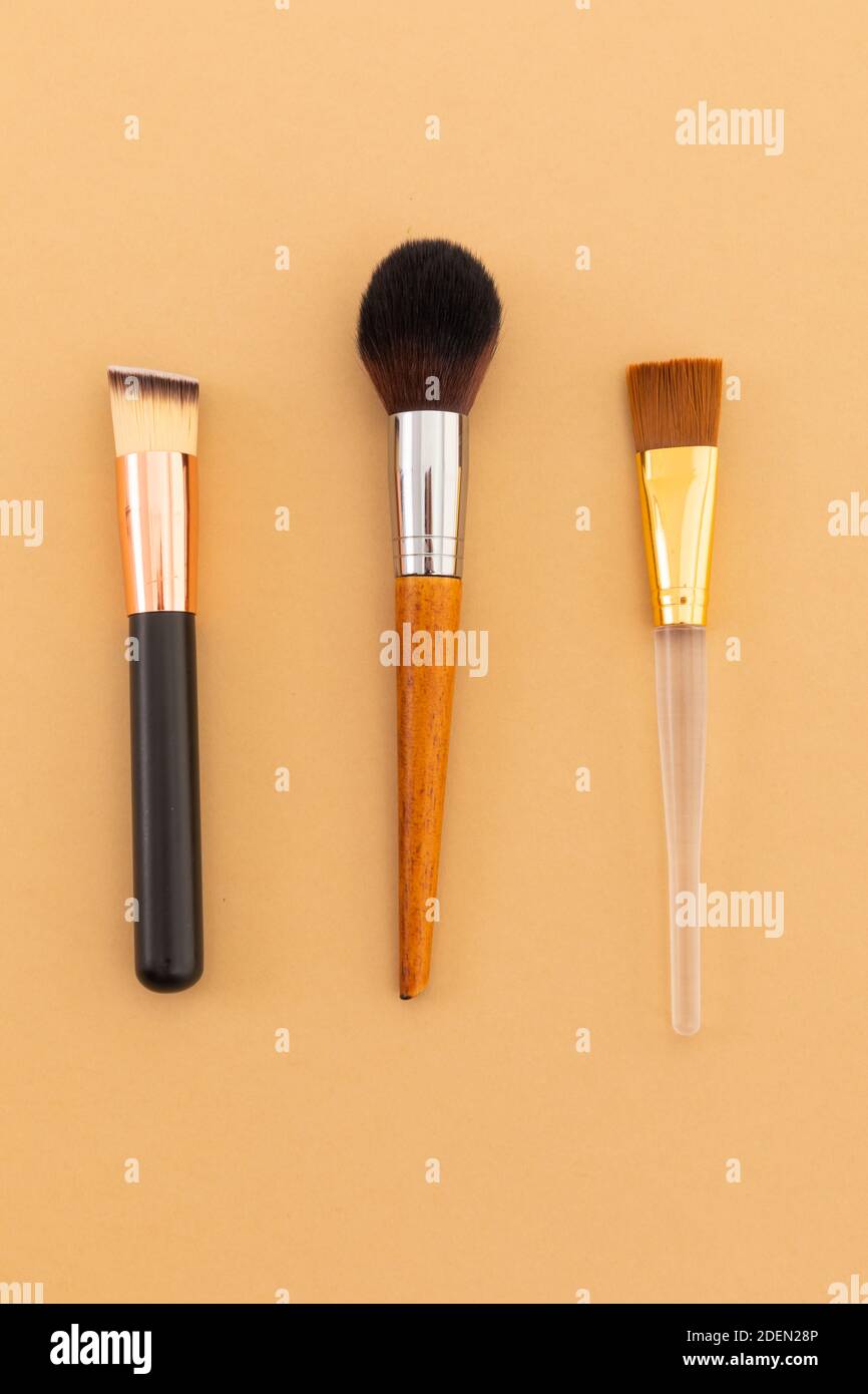 High angle view of three makeup brushes on yellow background Stock Photo