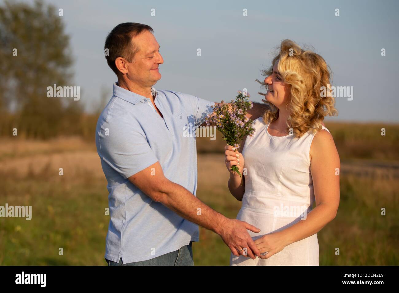 Beautiful middle-aged couple in love hugging on the background of nature. Stock Photo