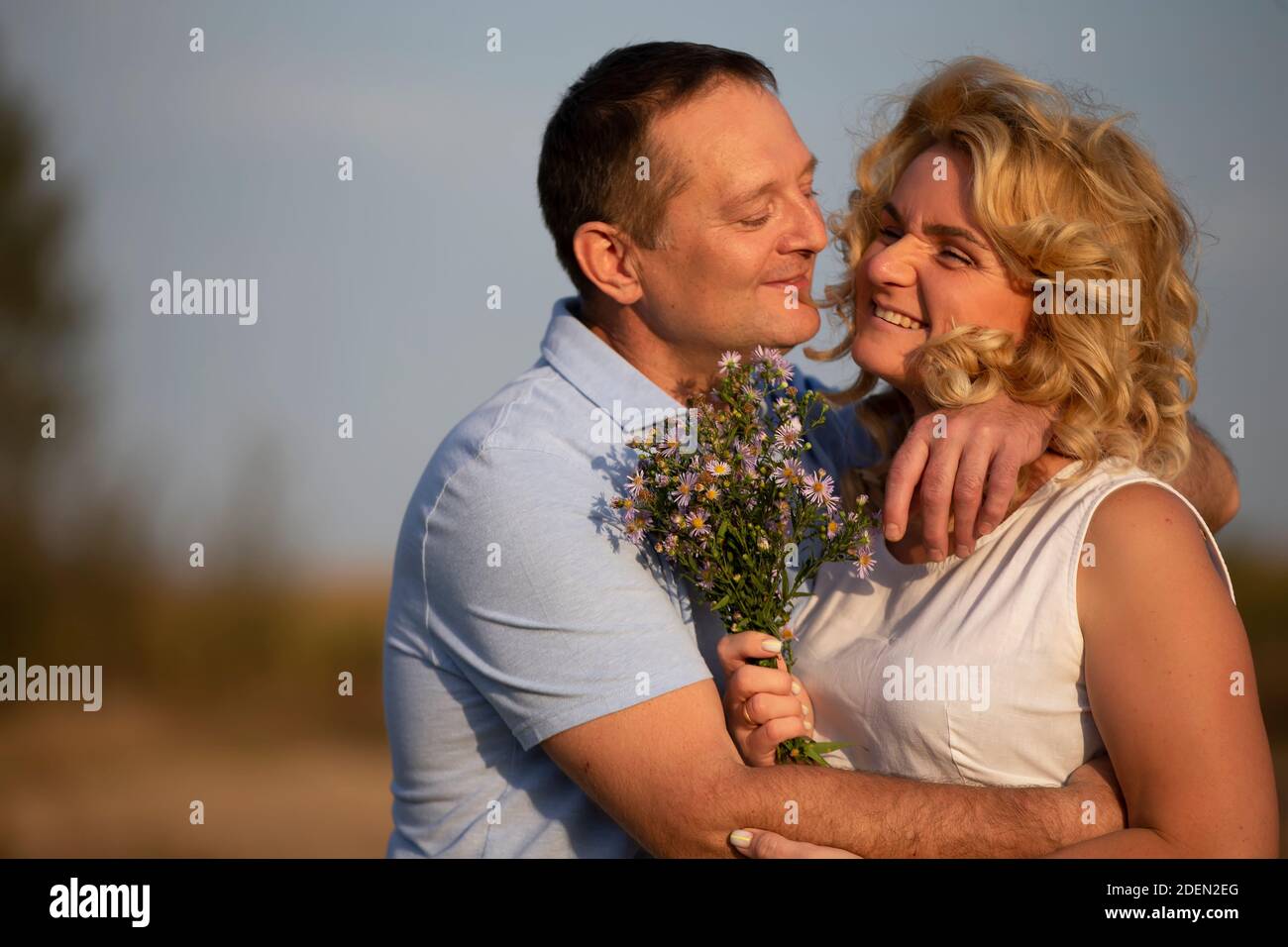 Beautiful middle-aged couple in love hugging on the background of nature. Stock Photo