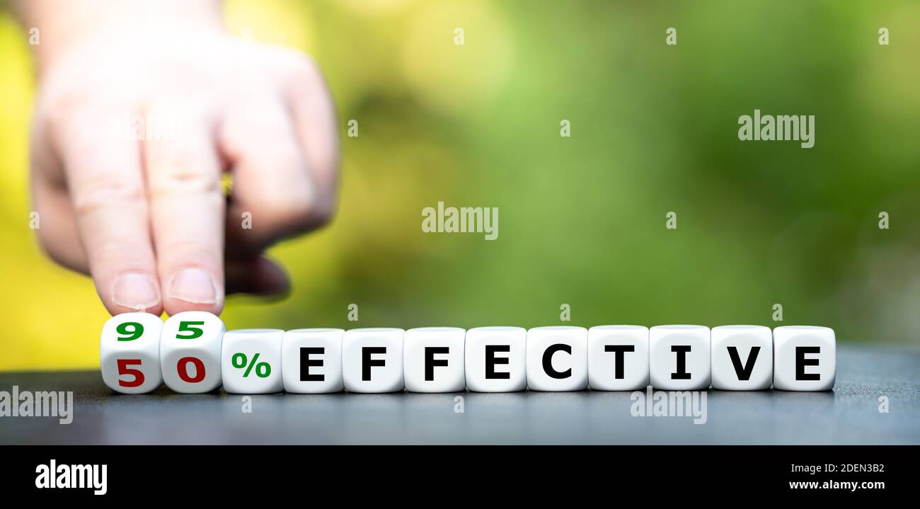 Symbol for the effectiveness of a corona vaccine. Hand turns dice and changes the expression "50% effective" to "95% effective". Stock Photo