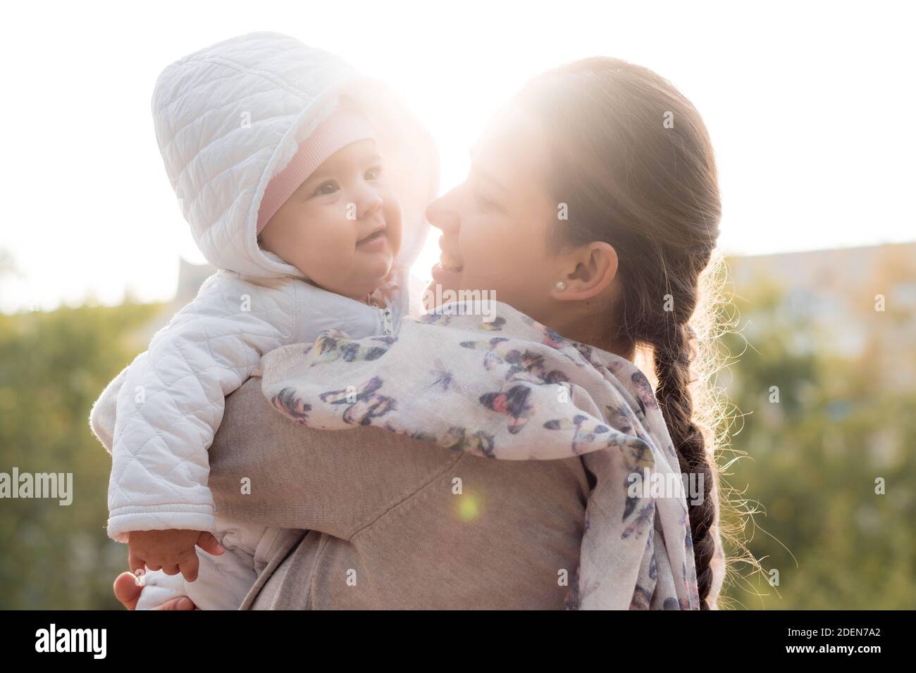 infants, childhood, motherhood, family, lifestyle concept - happy young mom in glasses hold fat chubby newborn smiling baby girl 6 months old in white Stock Photo