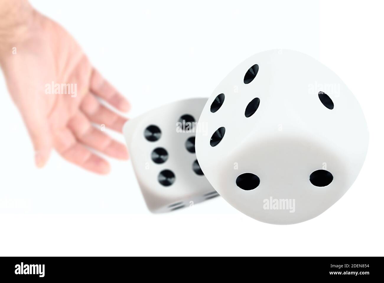 close-up view of hand of person throwing or rolling dice against white background Stock Photo