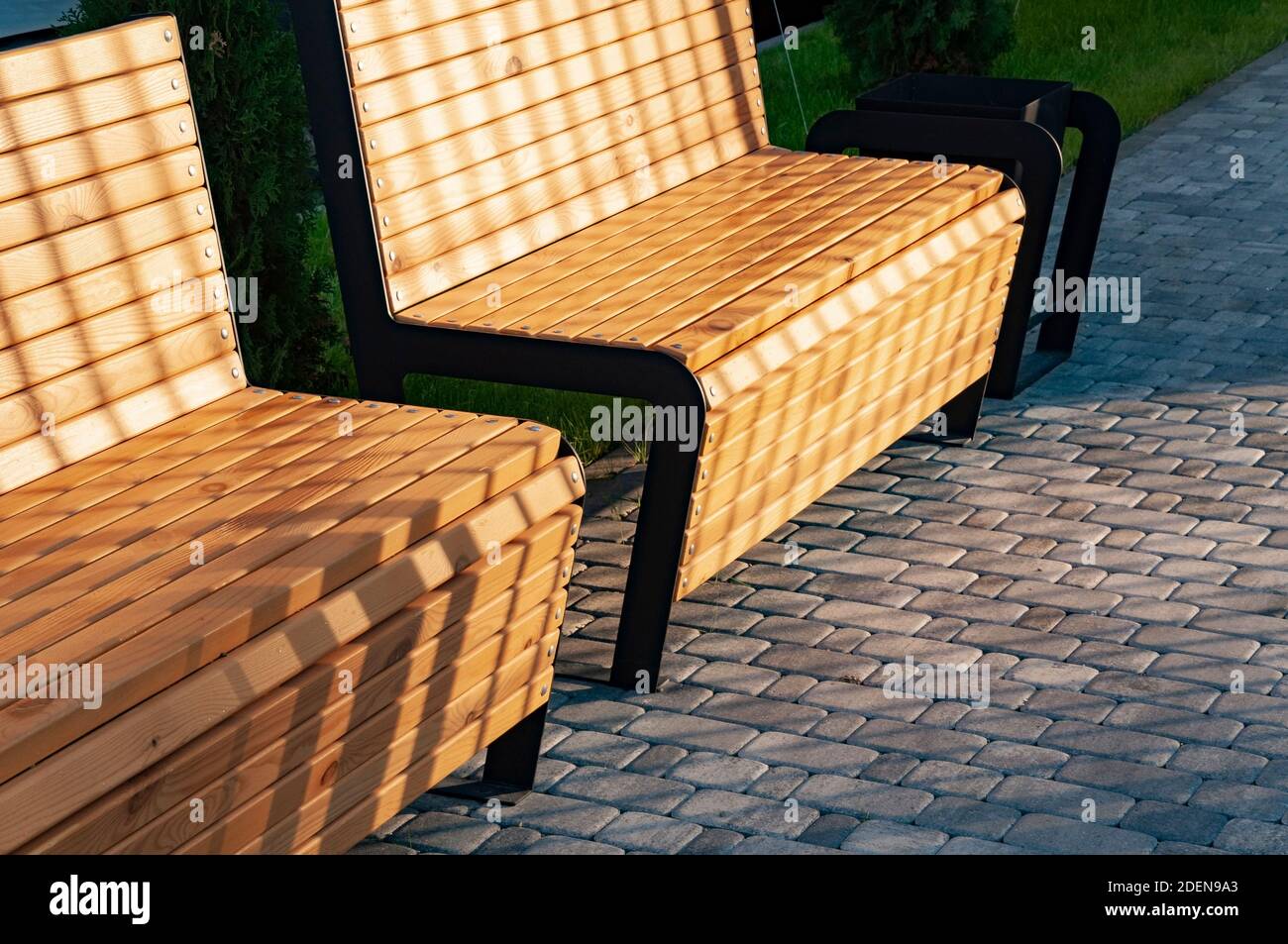 Two modern wooden benches on a cobblestone pavement Stock Photo