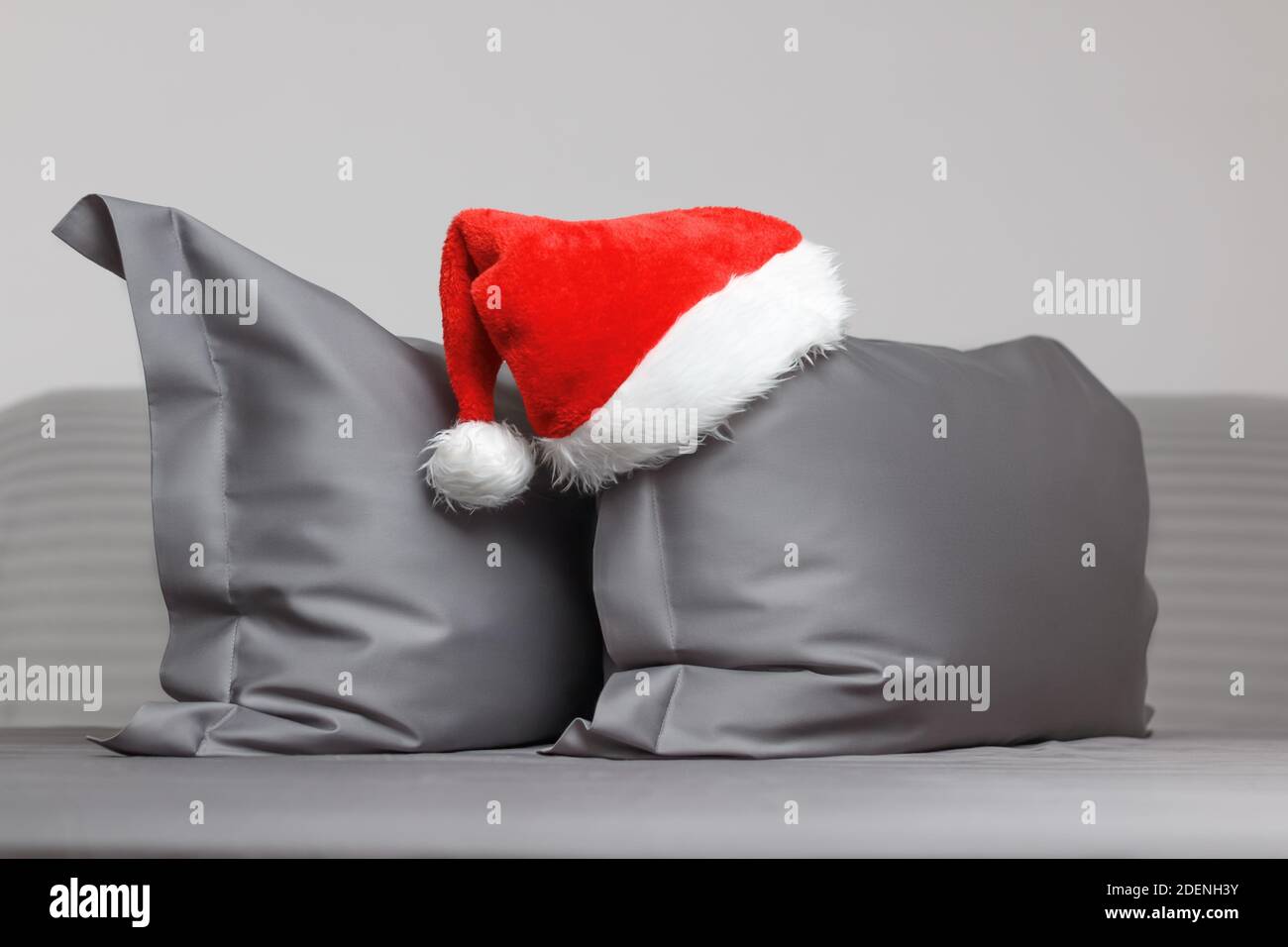 Gray feather pillows with a cap of Santa Claus. Stock Photo