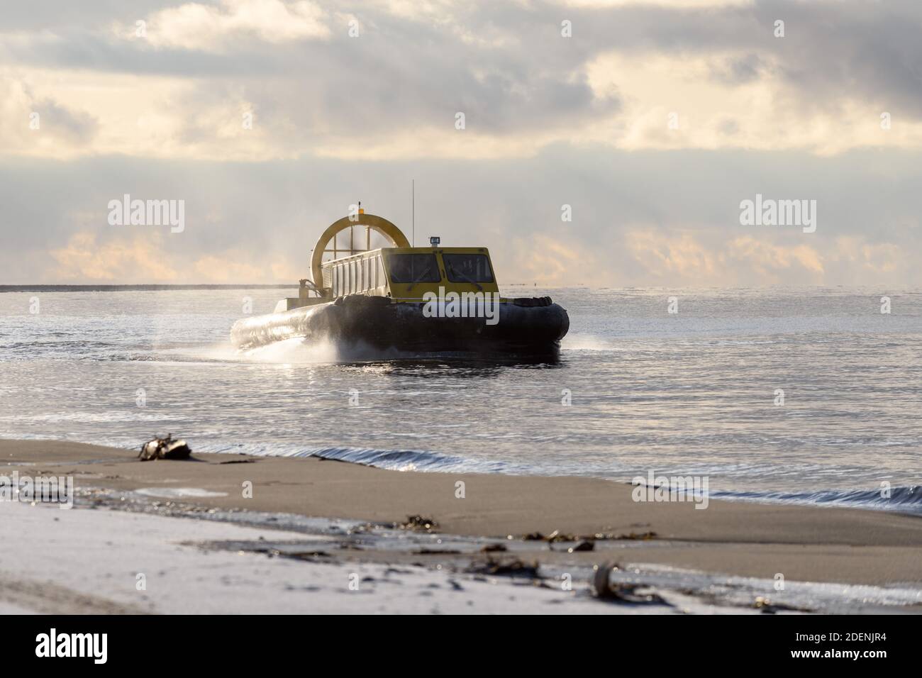 Hovercraft flying above water. Air cushion sailing near beach. Yellow