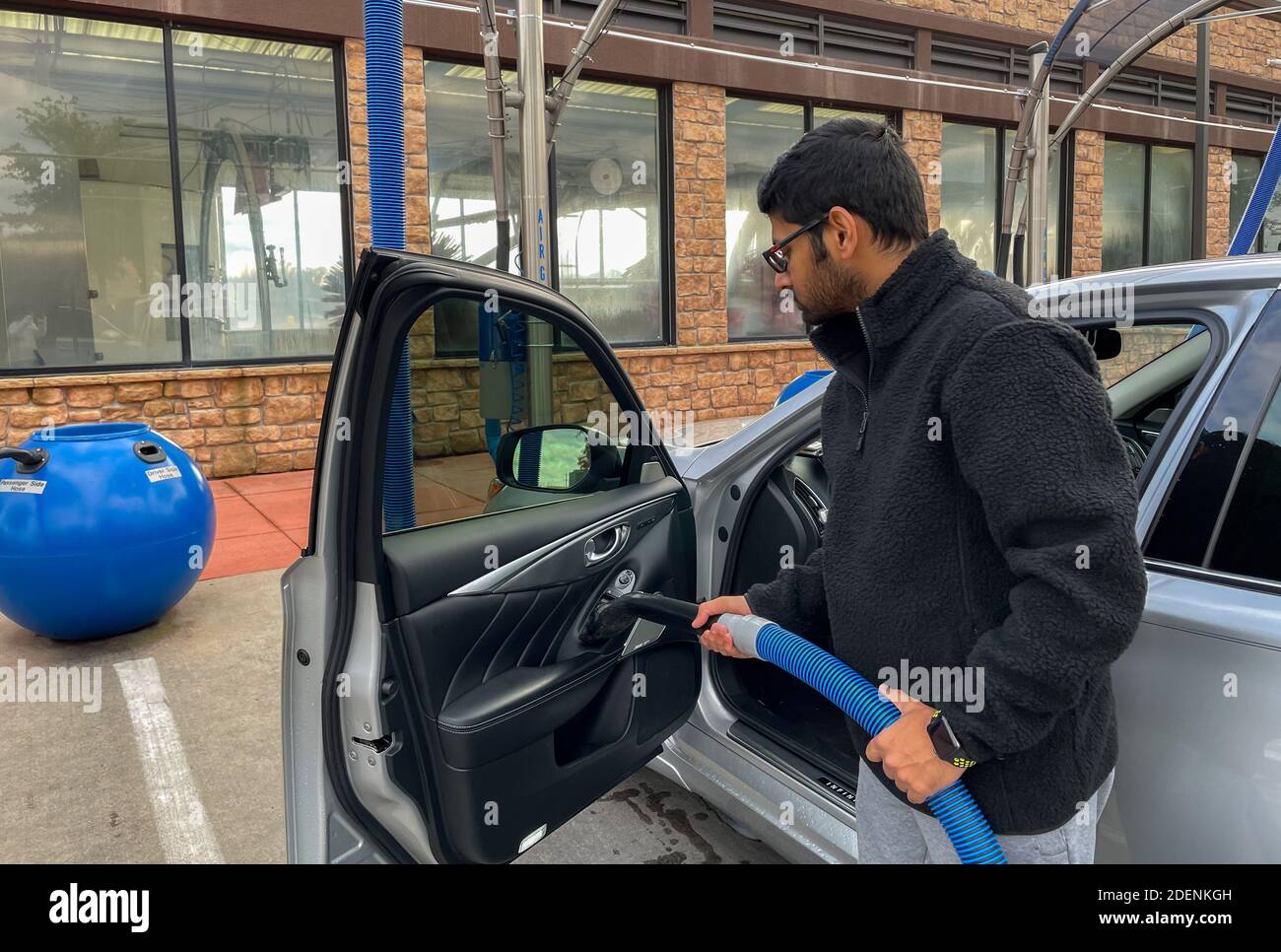 Mckinney, TX / USA - November 30, 2020: Close up view of a man using the vacuum hose to vacuum his car in the self serve vacuum parking lot Stock Photo