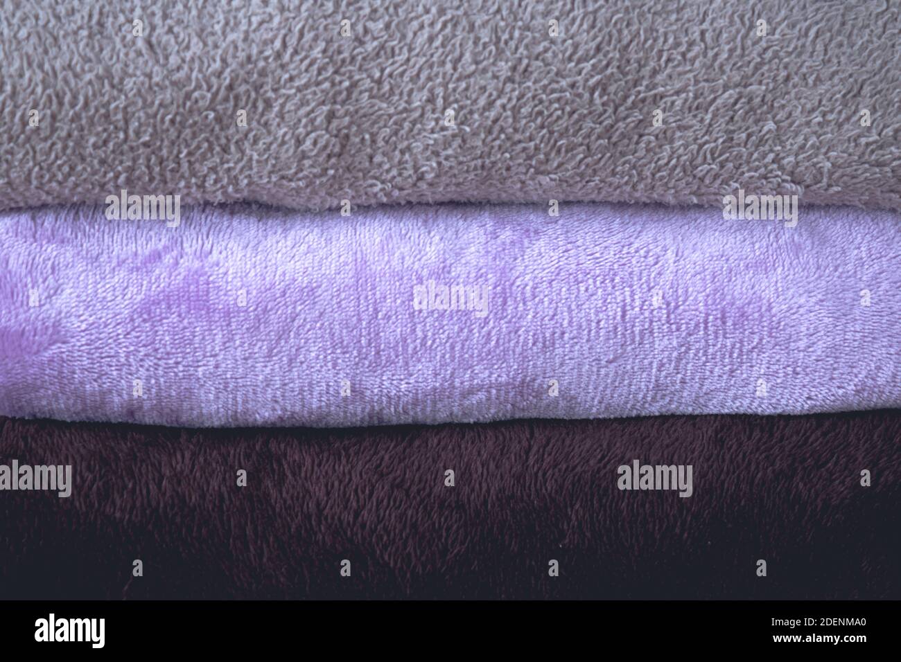 Winter blanket on a wooden table. Clothes with different patterns of fabric folded in pile. Winter bedding. Stock Photo
