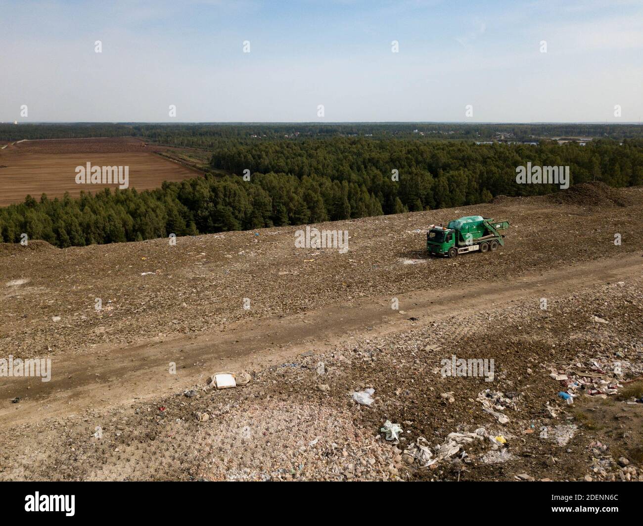 Top drone view of green garbage truck on dirt road near dump. Green