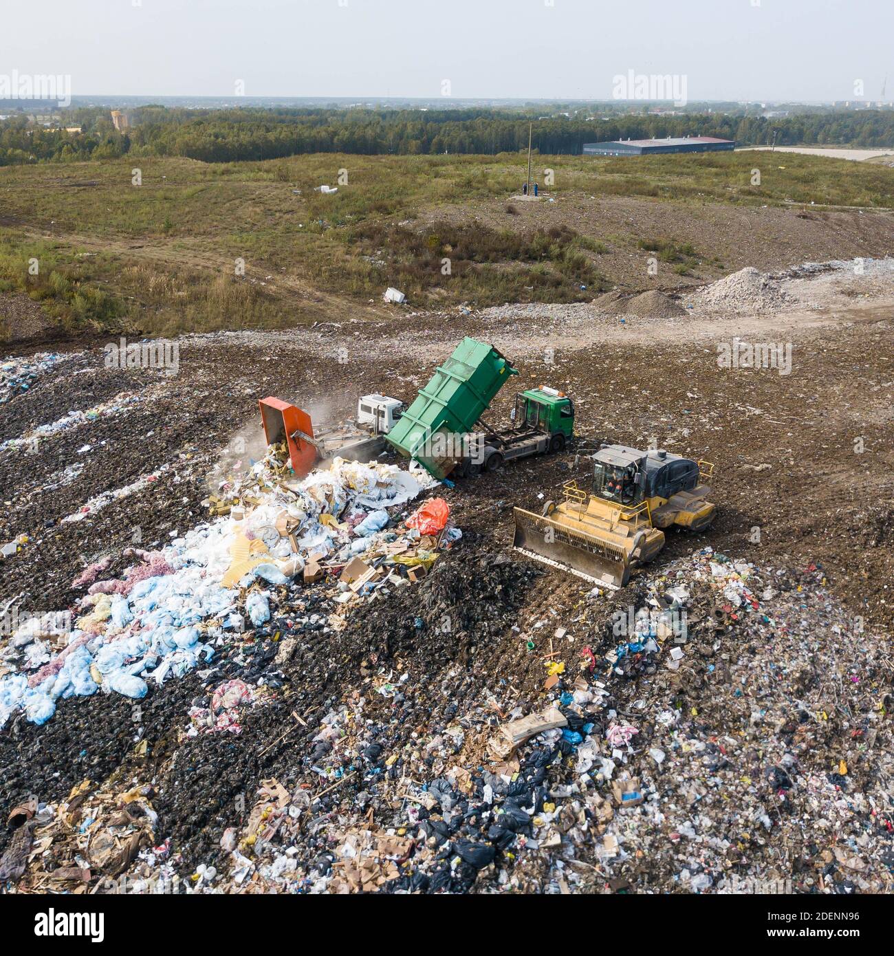 Aerial view of dump of big city. Garbage trucks unloading waste. Yellow tractor. Waste sorting