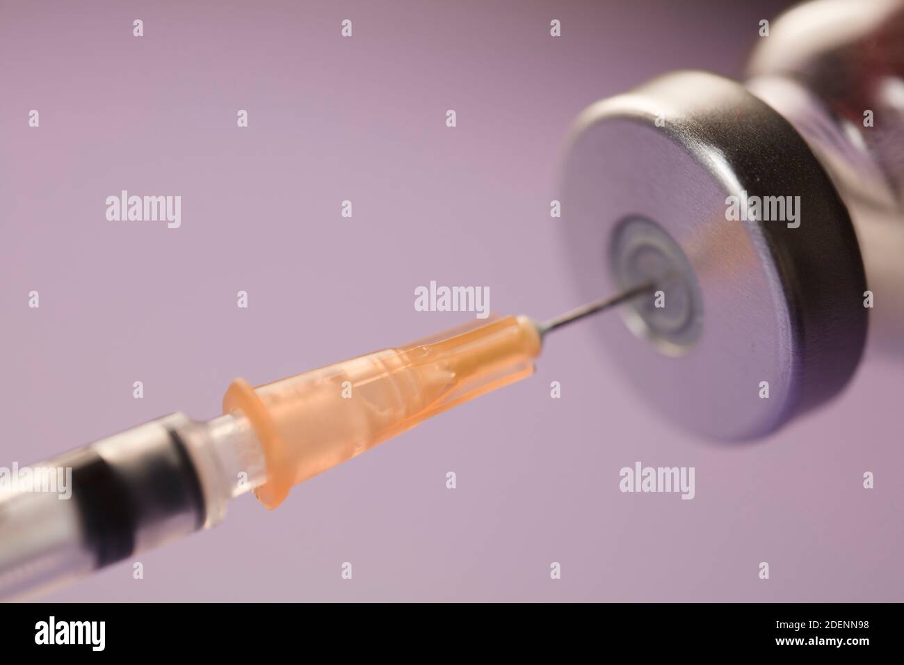 medical syringe cannula with vaccine vial, lilac background. macro