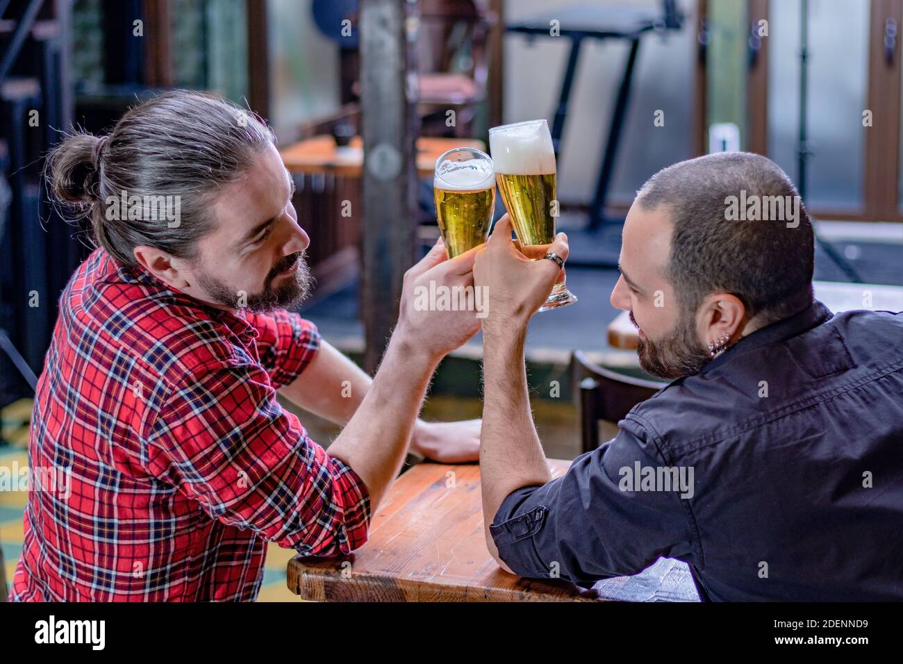 Two male friends drinking at the pub. They are laughing and toasting