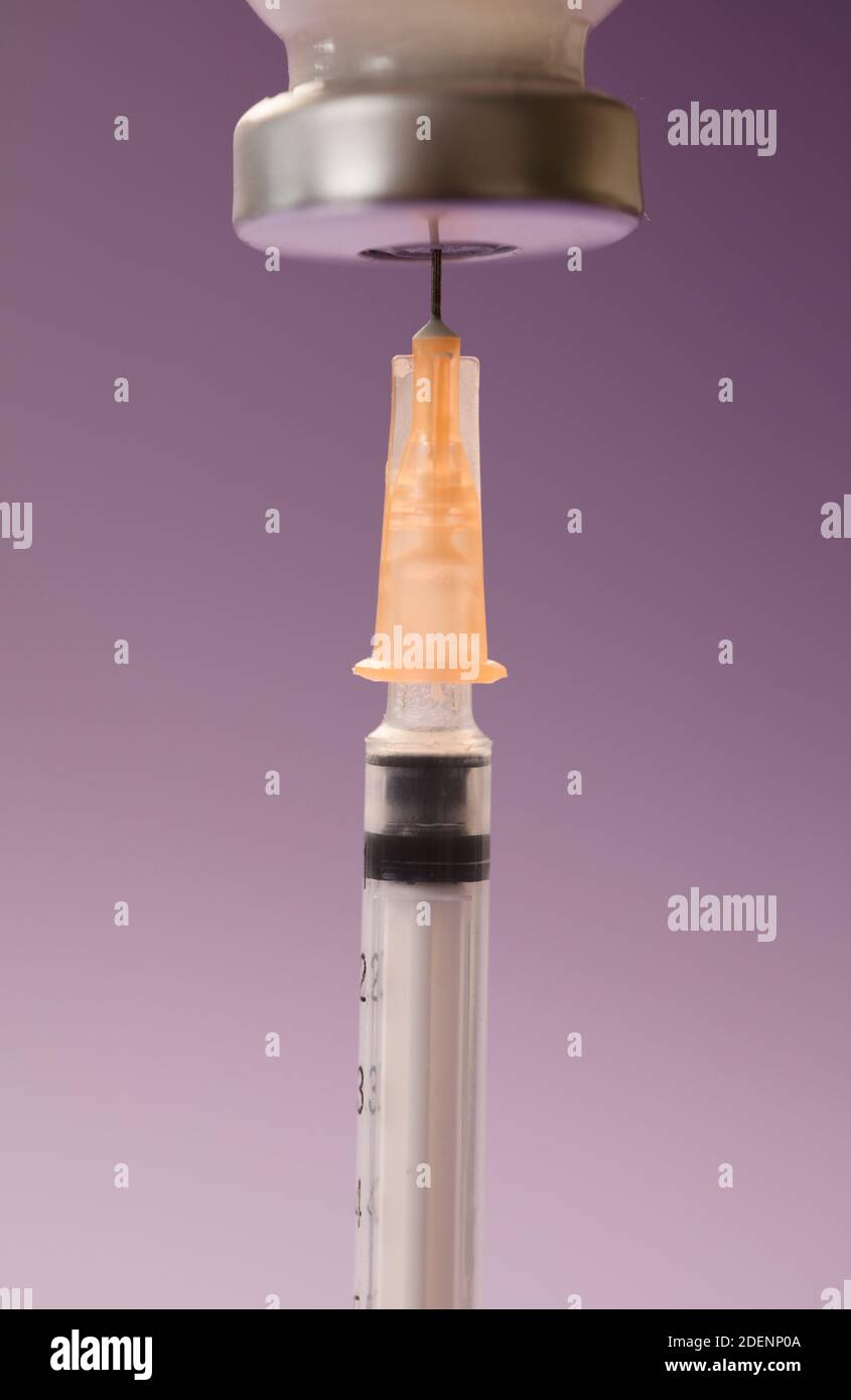 medical syringe cannula with vaccine vial, lilac background. macro