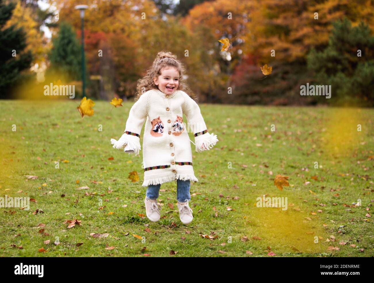 Little girl is playing with leaves in a park Stock Photo - Alamy