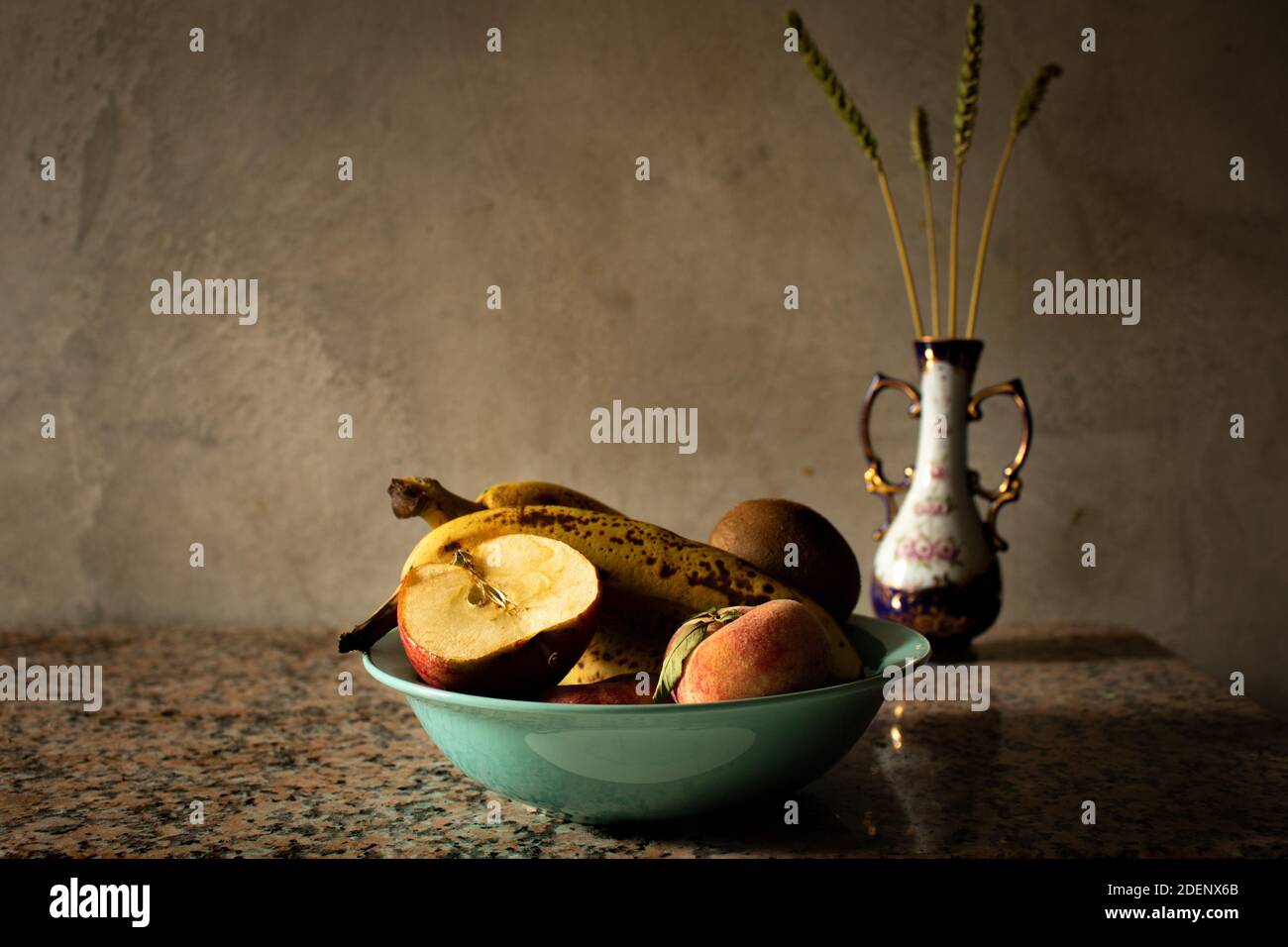 Still life of fruit sitting in a plate with ears of wheat in a jar blurring  in the background. Rustic mood with dim lights and golden tones Stock Photo  - Alamy