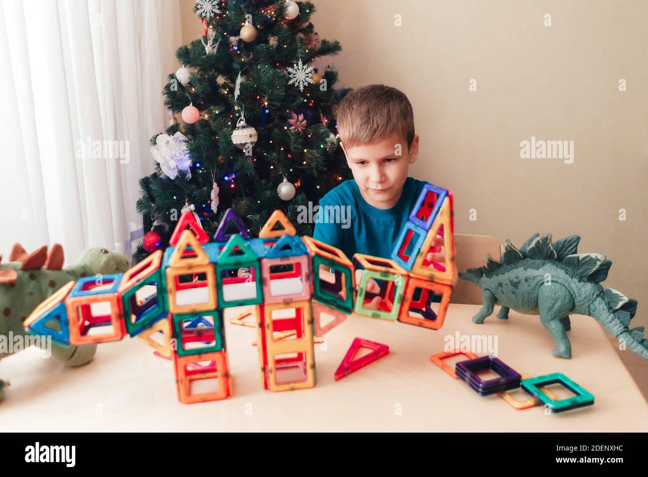 Child playing with magnetic constructor near by Christmas tree Stock Photo