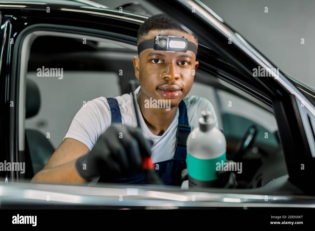 Close up of African man, car detailing service worker, cleaning car