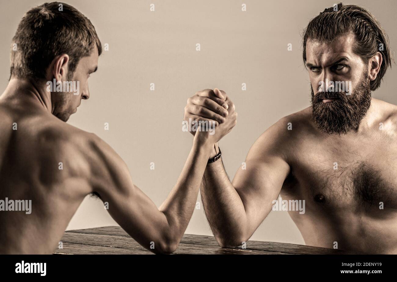 Arms wrestling thin hand, big strong arm in studio. Two man's hands