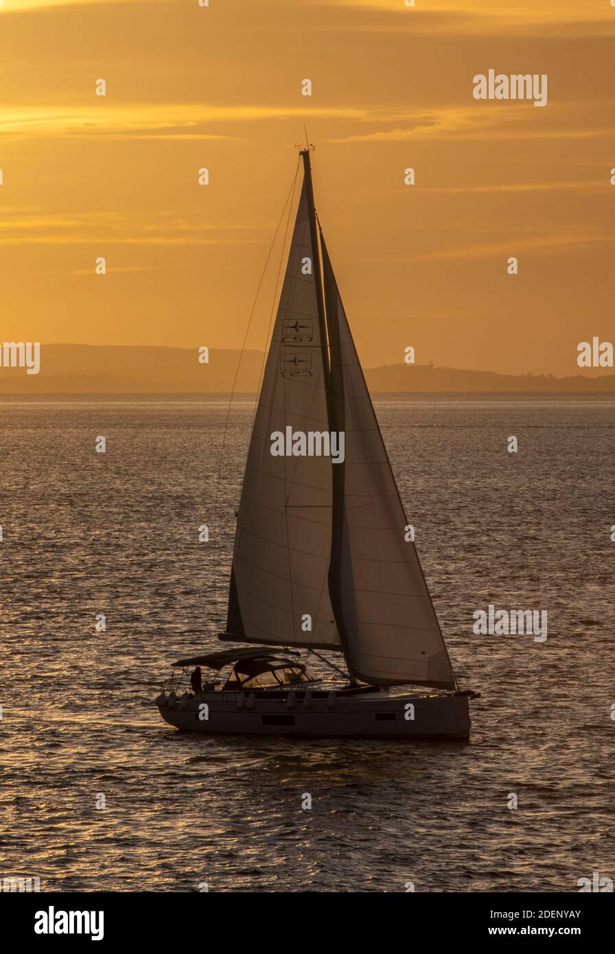 a sailing yacht in silhouette against a golden glowing sunset sky Stock ...