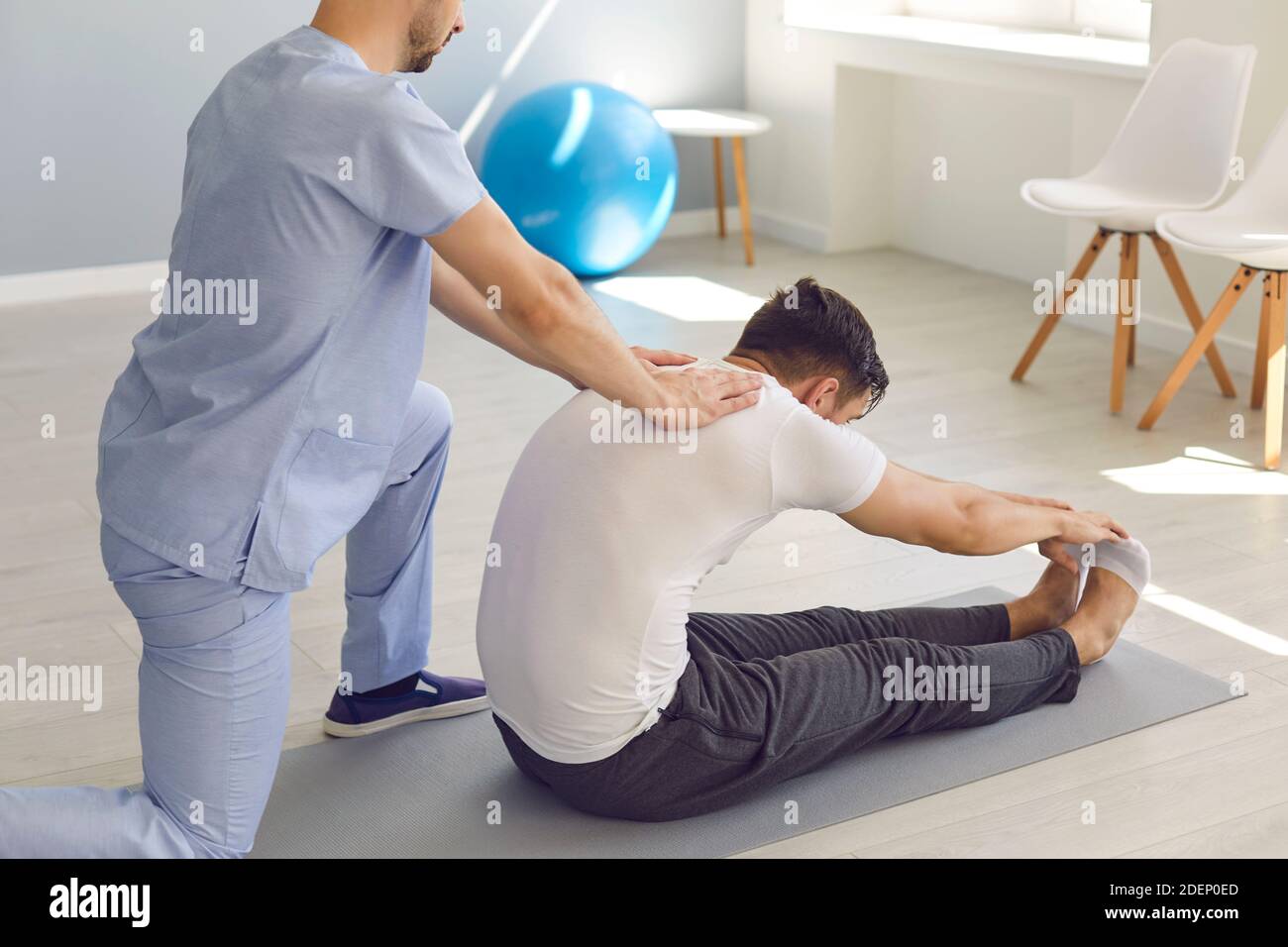 Side view doctor helps the patient to do stretching exercises and yoga after the injury. Stock Photo
