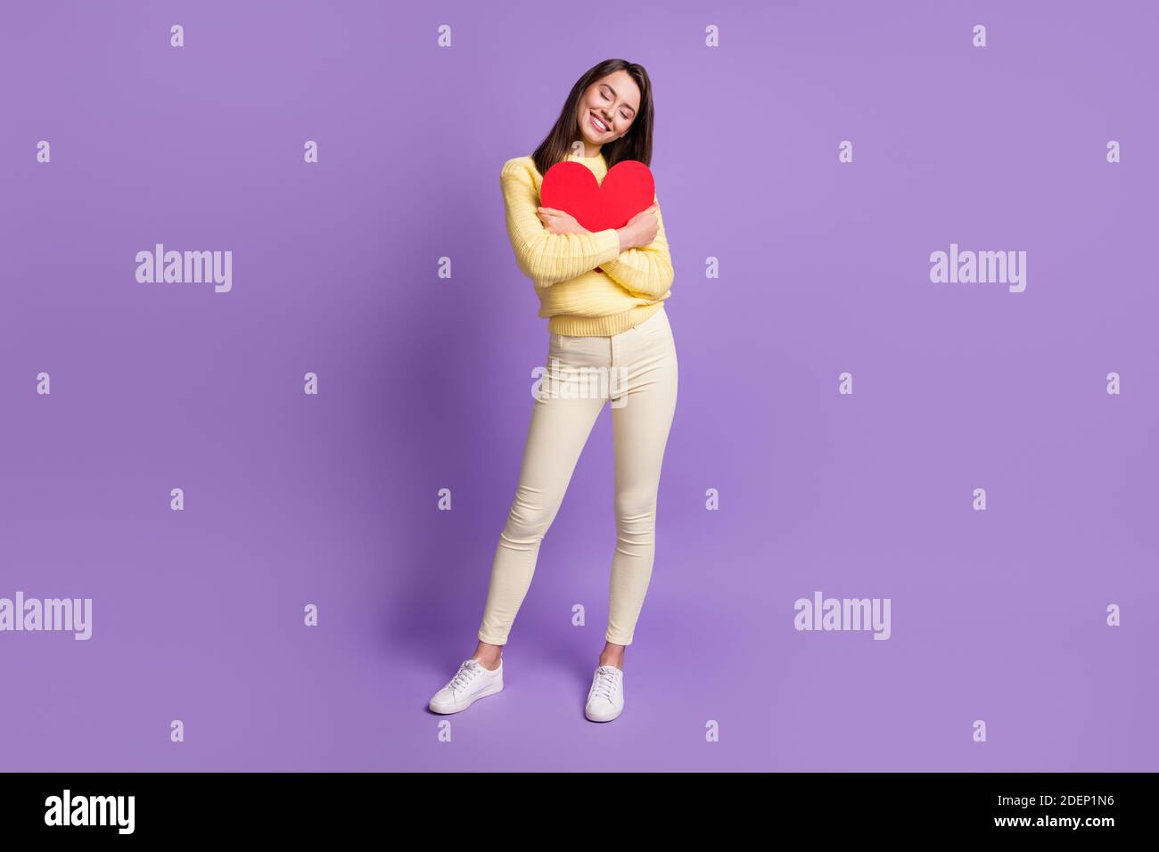 Full length body size photo of nice girlfriend embracing big red paper heart postcard for valentine day isolated on vibrant violet color background Stock Photo