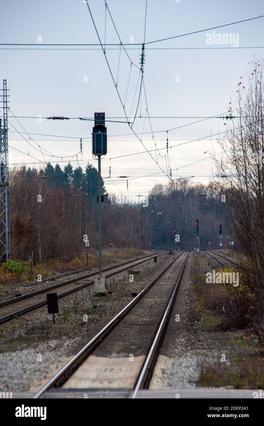 Railway tracks with overhead lines and red traffic lights in portrait format Stock Photo