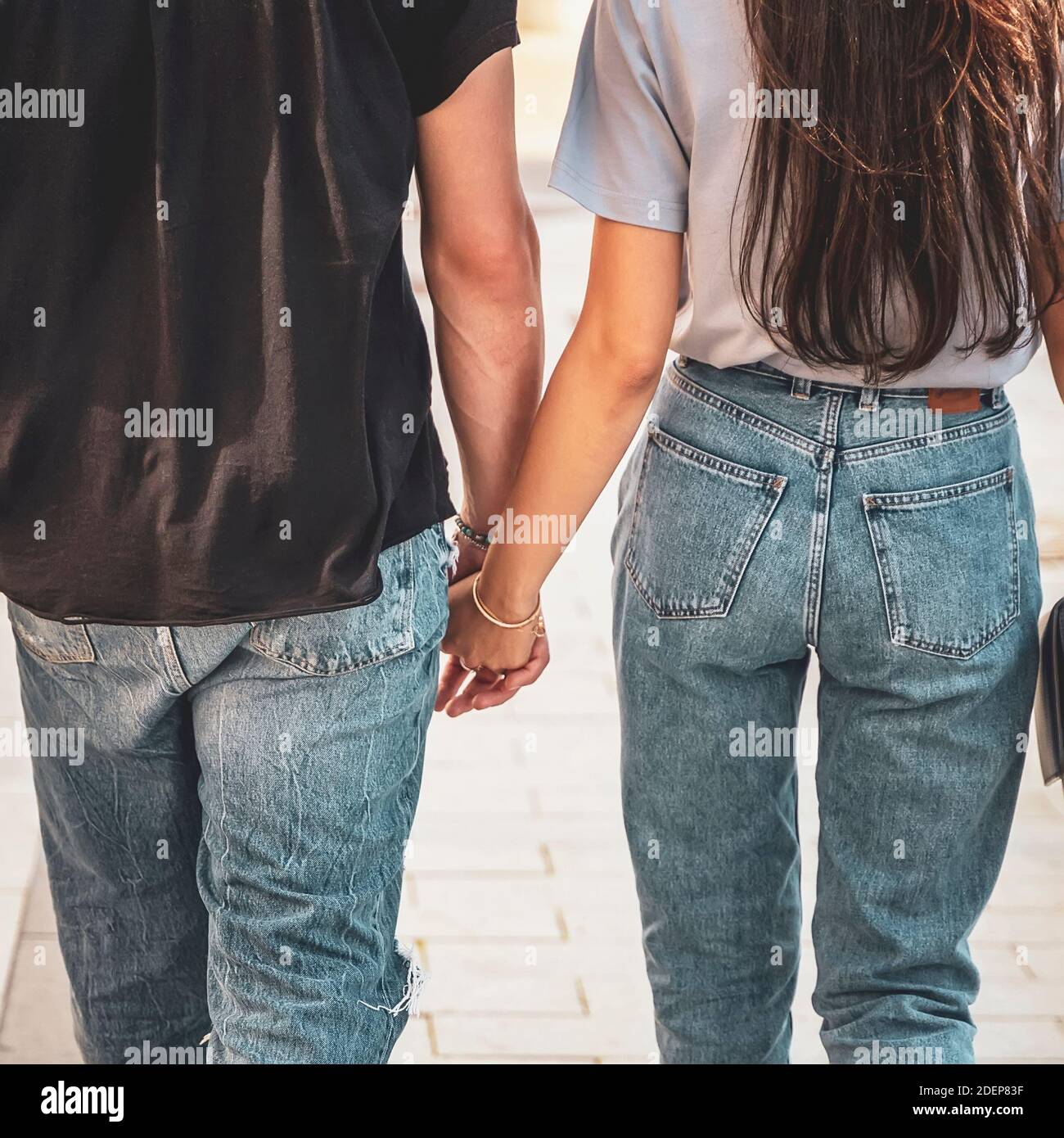 Holding Hands close-up of unrecognizable couple from behind, romantic joint walk Stock Photo