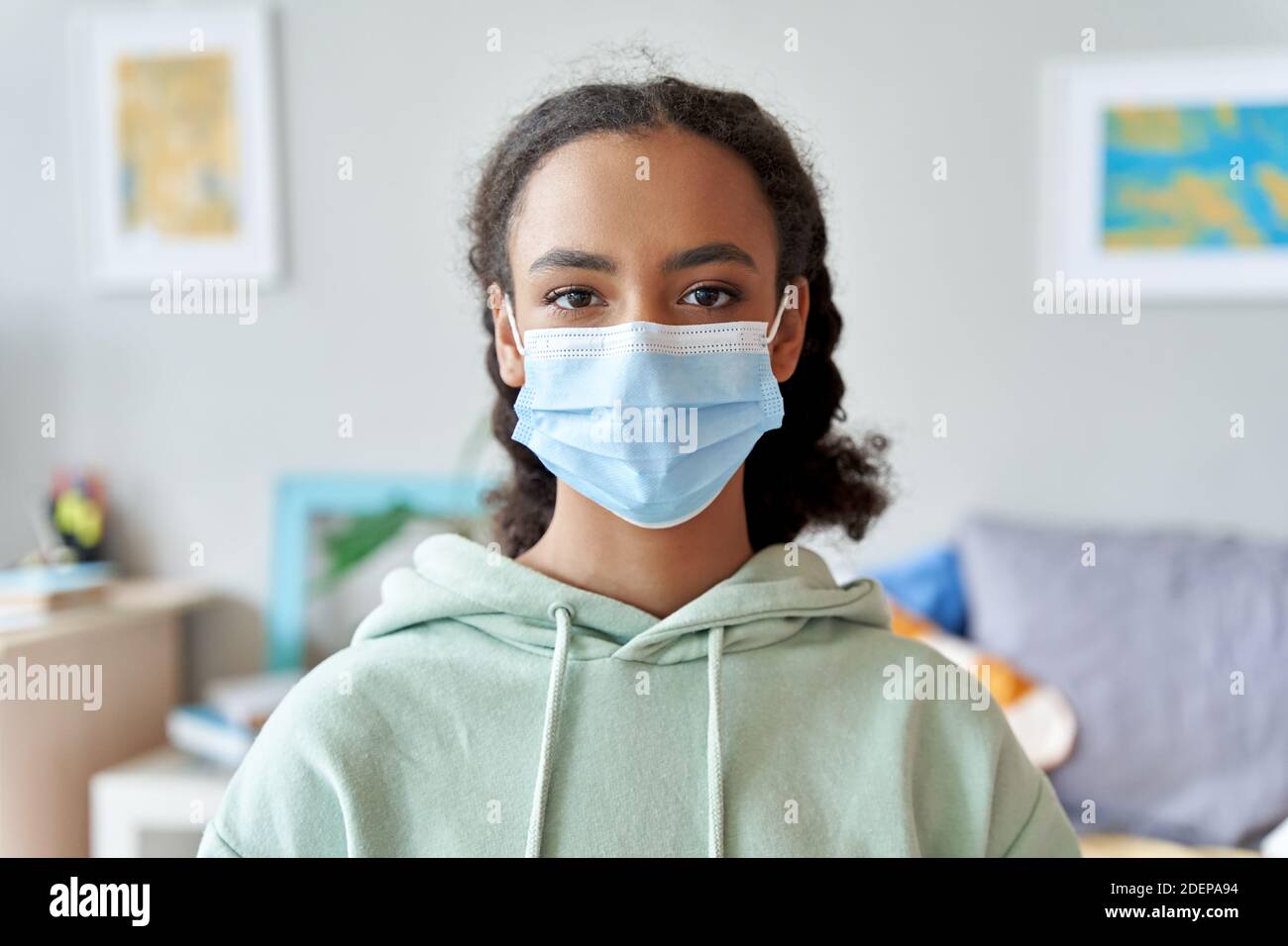 African american teen girl wearing face mask looking at camera at home. Stock Photo