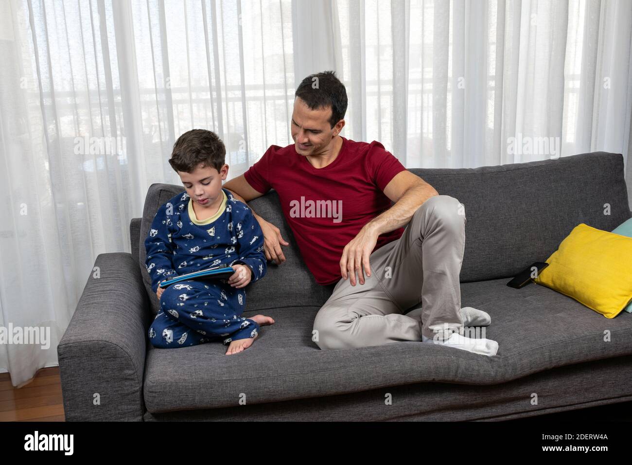 Mature man (44 years old) sitting next to his son (6 years old) and smiling at him. Stock Photo