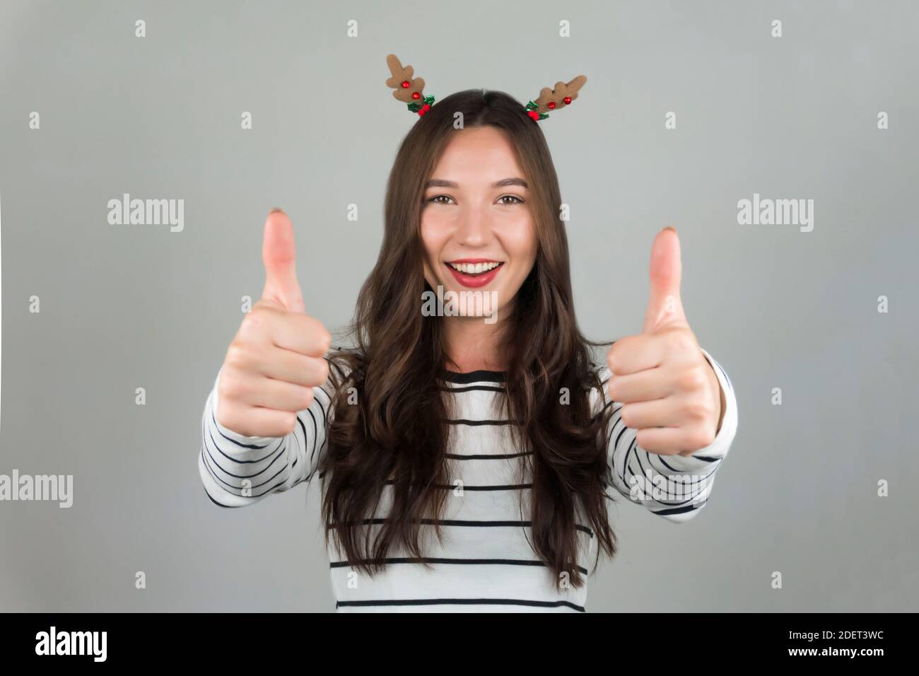 Happy woman with thumbs up. Christmas decorations in hair. High quality photo Stock Photo