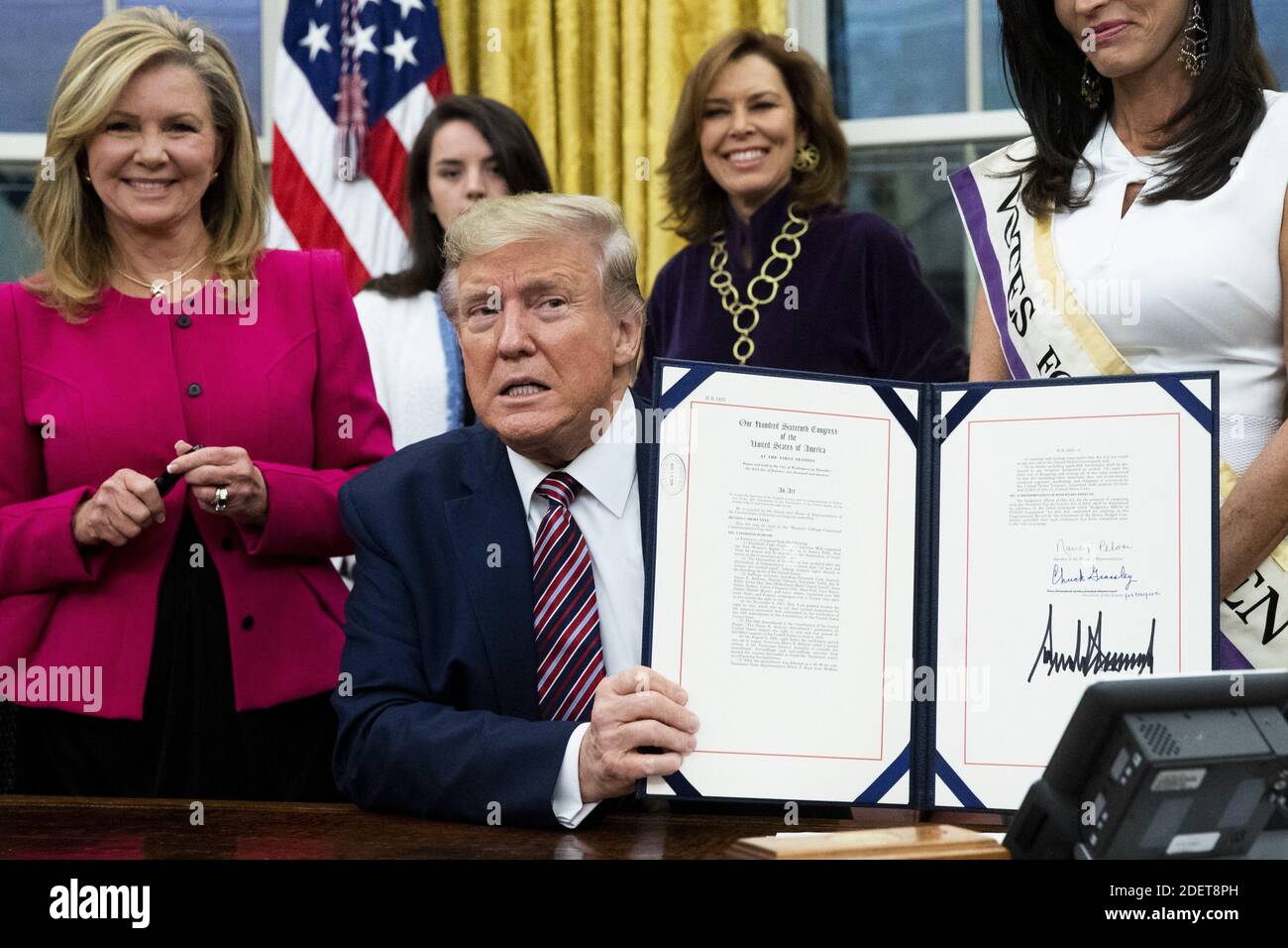 US President Donald J. Trump (C) holds up 'the WomenâÂ€Â™s Suffrage Centennial Commemorative Coin Act', after signing it during a ceremony, beside Republican Senator from Tennessee Marsha Blackburn (L), in the Oval Office of the White House in Washington, DC, USA, 25 November 2019. Trump signed 'H.R. 2423, the WomenâÂ€Â™s Suffrage Centennial Commemorative Coin Act' - a bill directing the US Treasury to mint and issue up to four hundred thousand one-dollar silver coins honoring women that played a role in gathering support for the 19th Amendment. Photo by Michael Reynaolds/Pool/ABACAPRESS.COM Stock Photo
