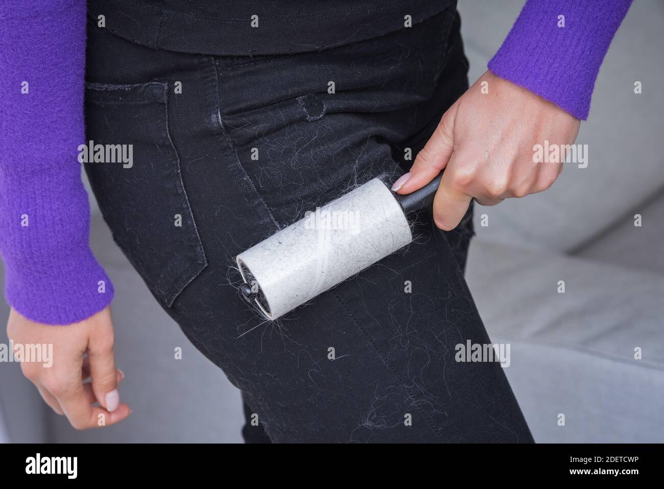 Woman cleans clothes with clothes roller, lint roller or sticky roller.  Cleaning pets hair on the dark clothes Stock Photo - Alamy