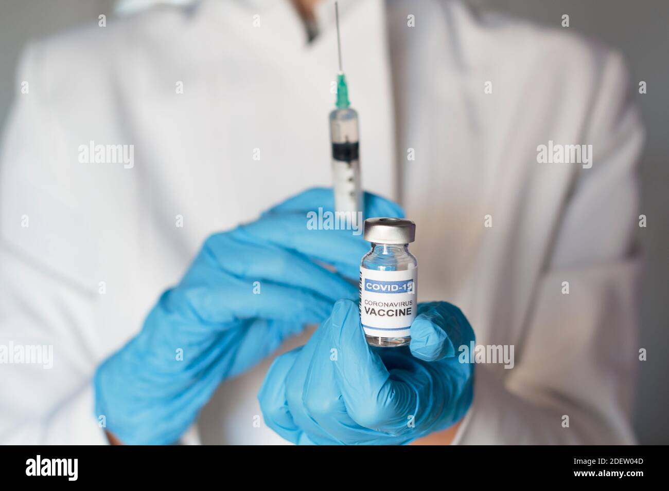Doctor holding syringe and laboratory injection vial with Coronavirus ...