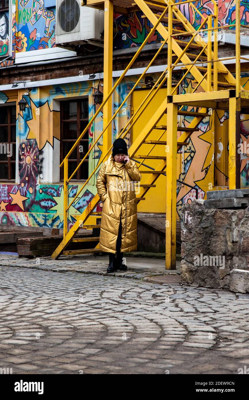 An older woman in a yellow coat is talking on the phone Stock Photo