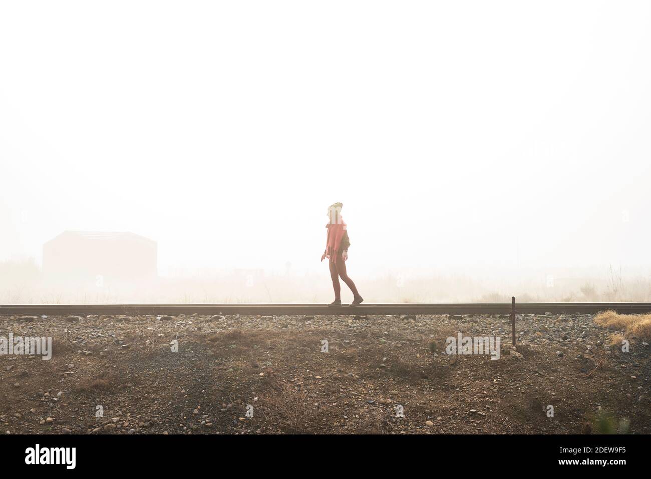 Side view of a girl balancing on train rail while walking Stock Photo