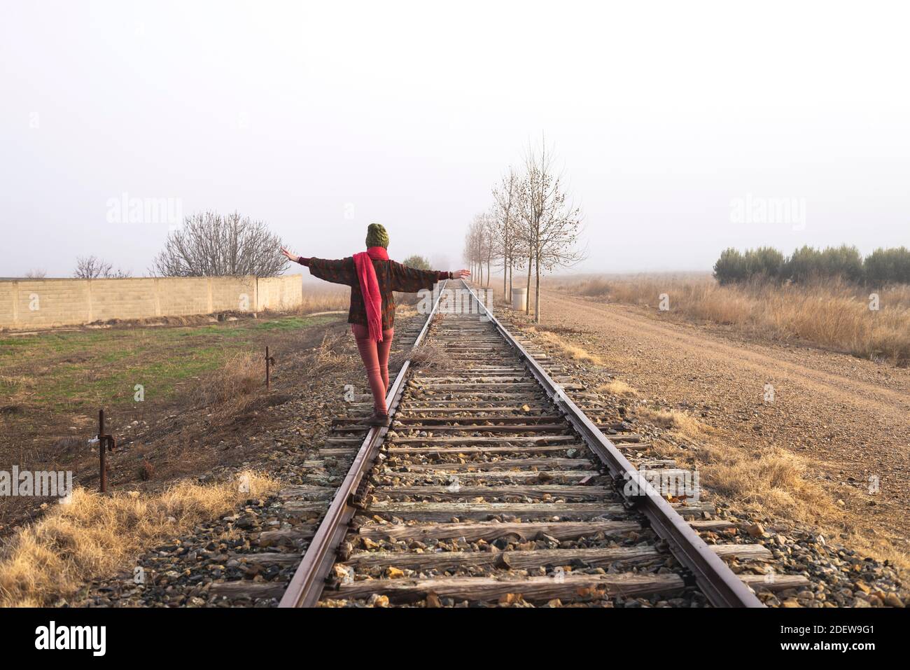 Rear view of a girl balancing on train rail while walking Stock Photo