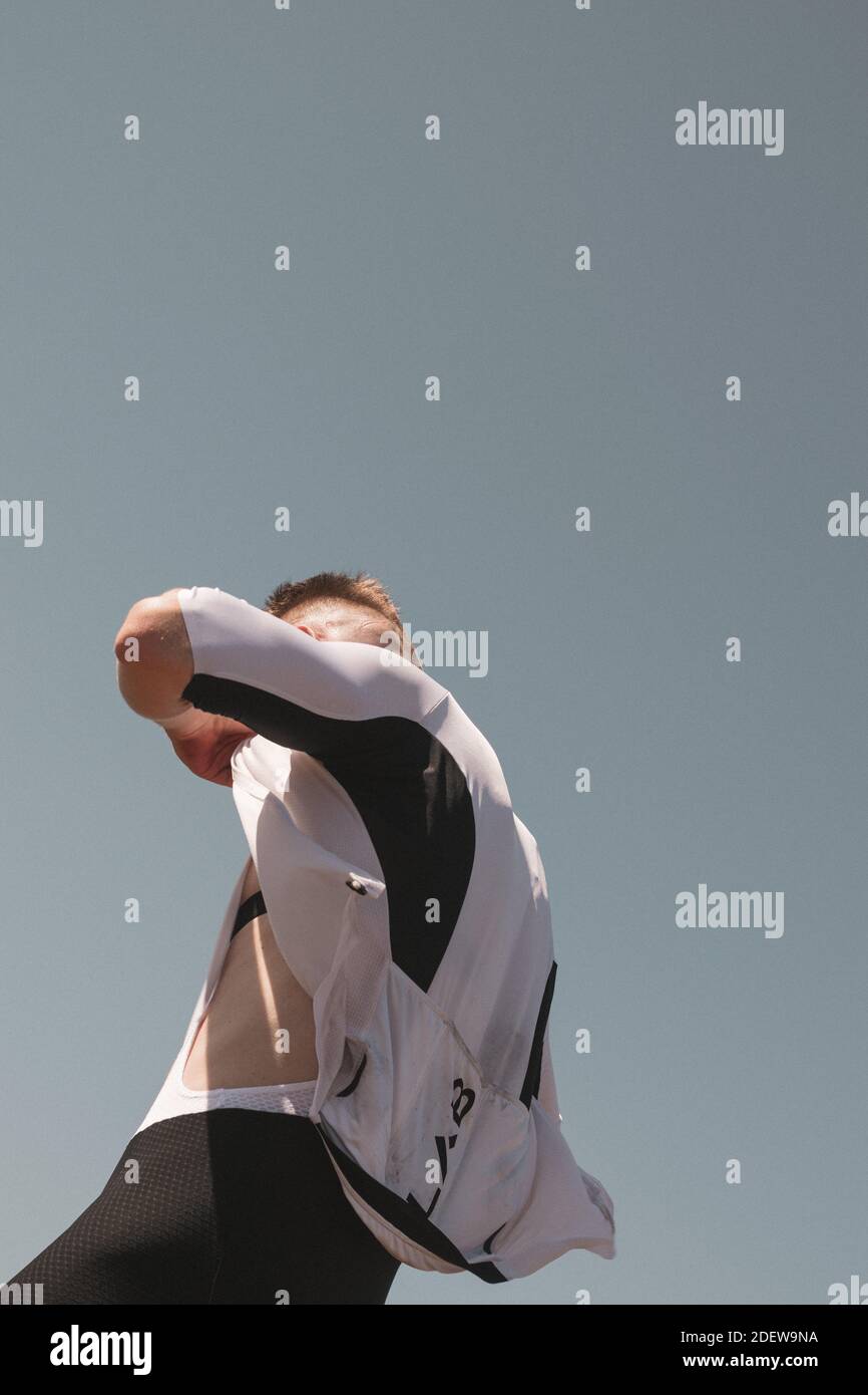 Cyclist unzips jersey during summer from below perspective Stock Photo