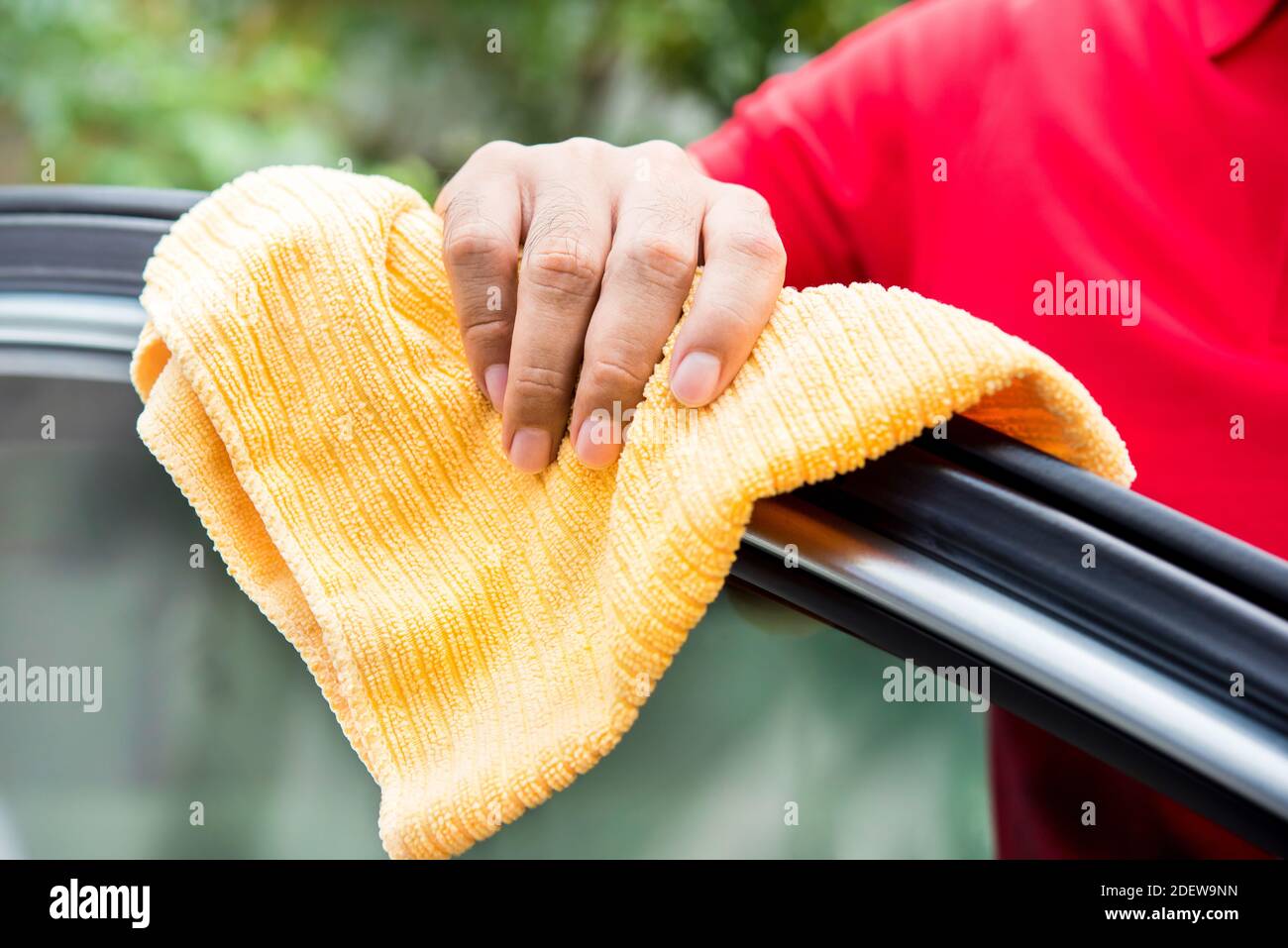 Male auto care service staff cleaning car window with microfiber cloth Stock Photo