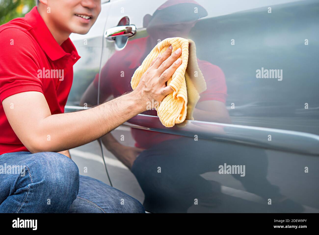 Male auto care service staff cleaning car door with microfiber cloth Stock Photo