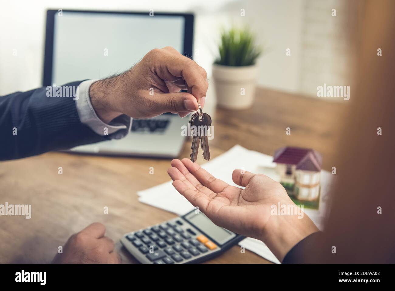 Real estate broker agent giving house keys to client after finish making rental agreement in the office Stock Photo